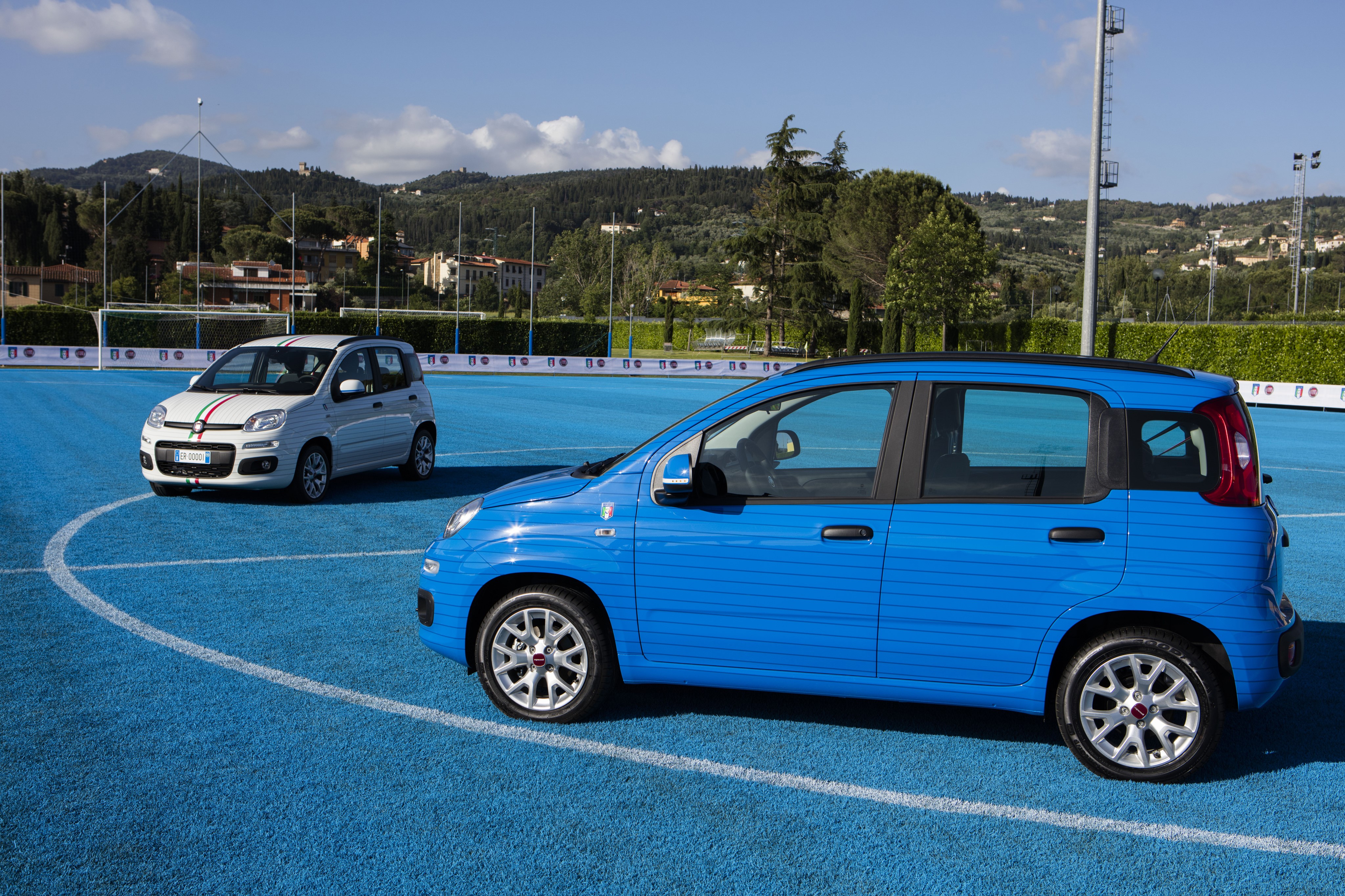 Two Fiat Panda cars on a blue sports field HD Wallpaper