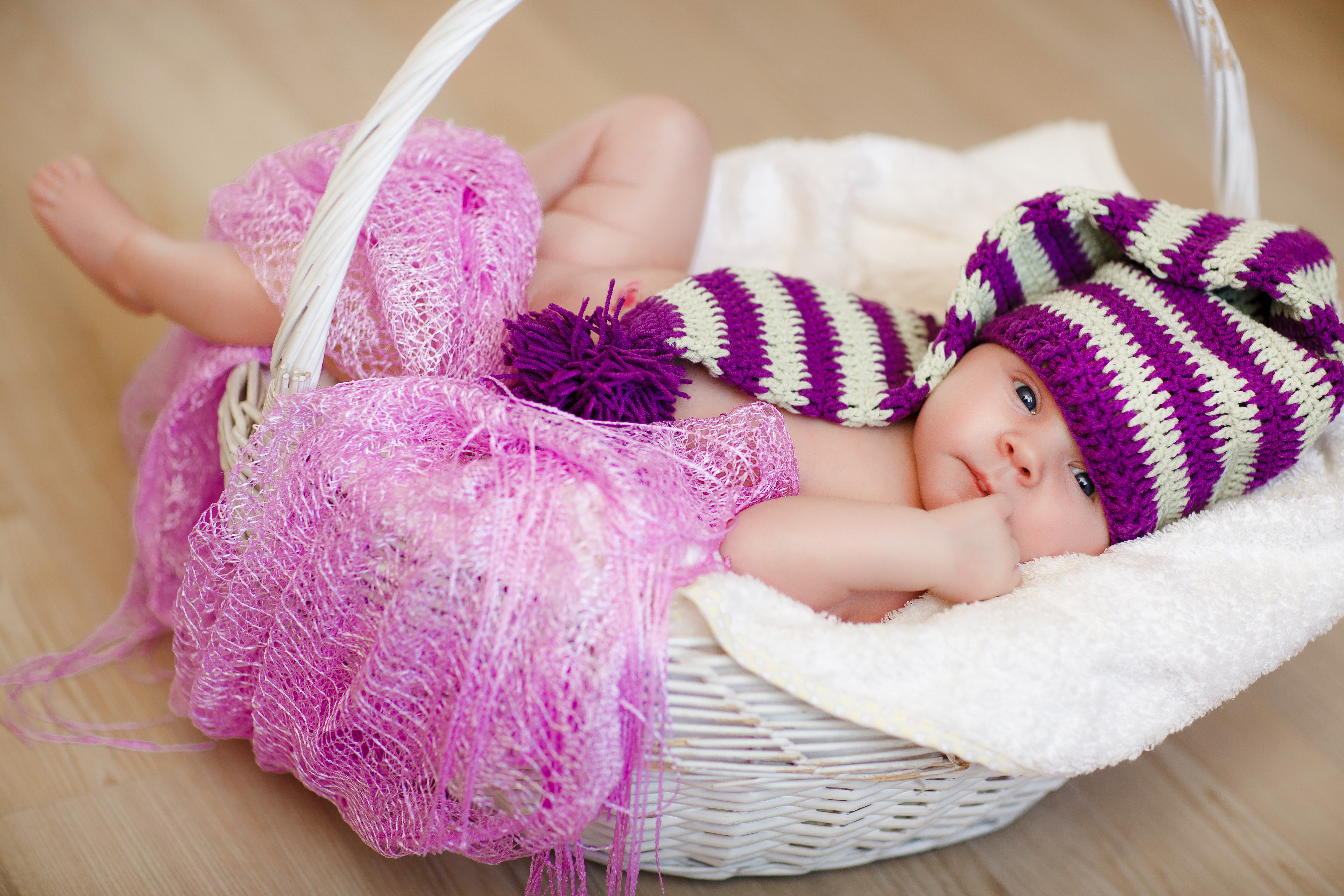 Baby in a striped winter hat in a wicker basket HD Wallpaper