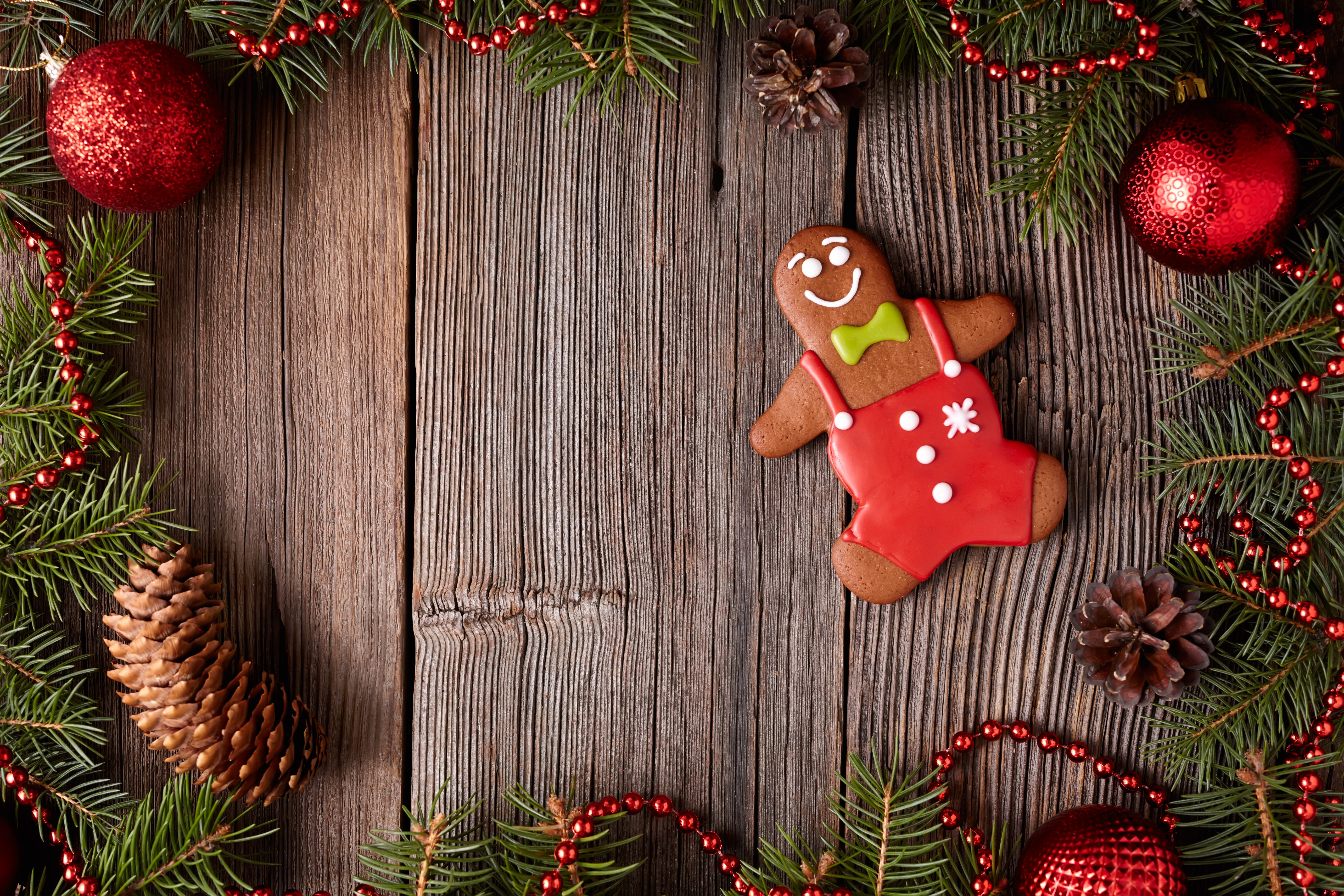 Christmas gingerbread man cookie on wooden background with pine cones and ornaments HD Wallpaper