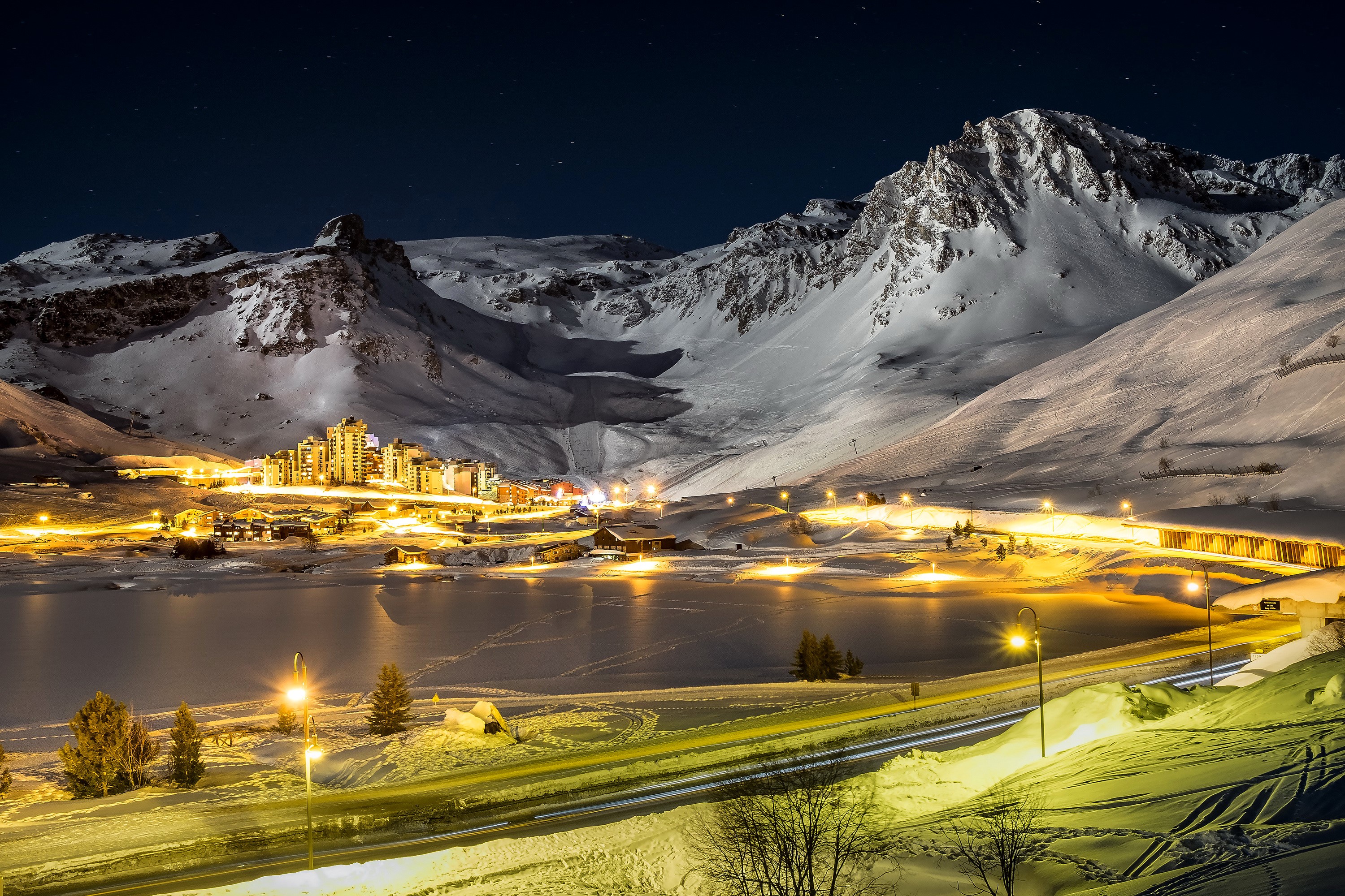 Tignes, France at night with snow-covered mountains and lake HD Wallpaper