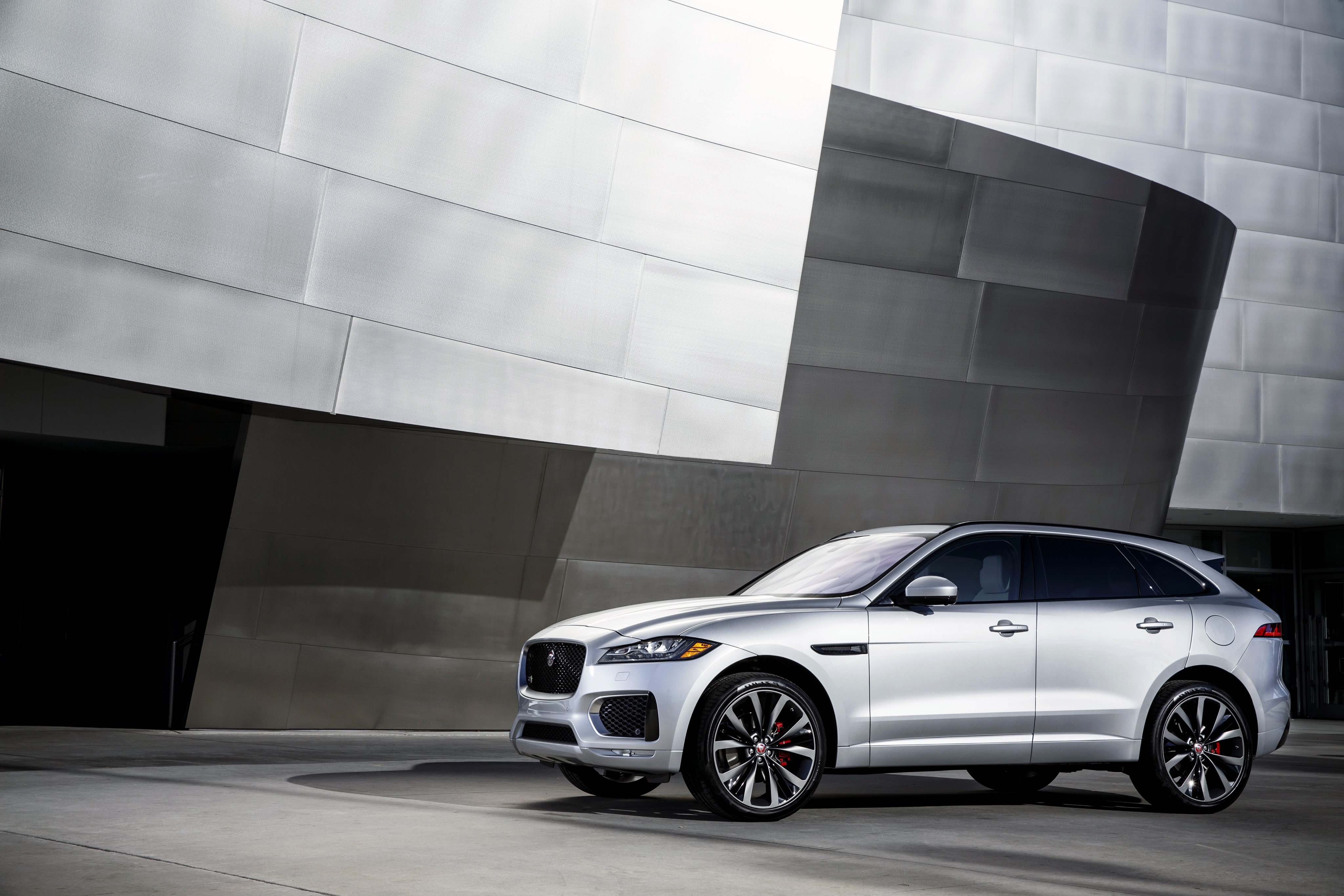 Silver Jaguar F-Pace parked near a modern building HD Wallpaper