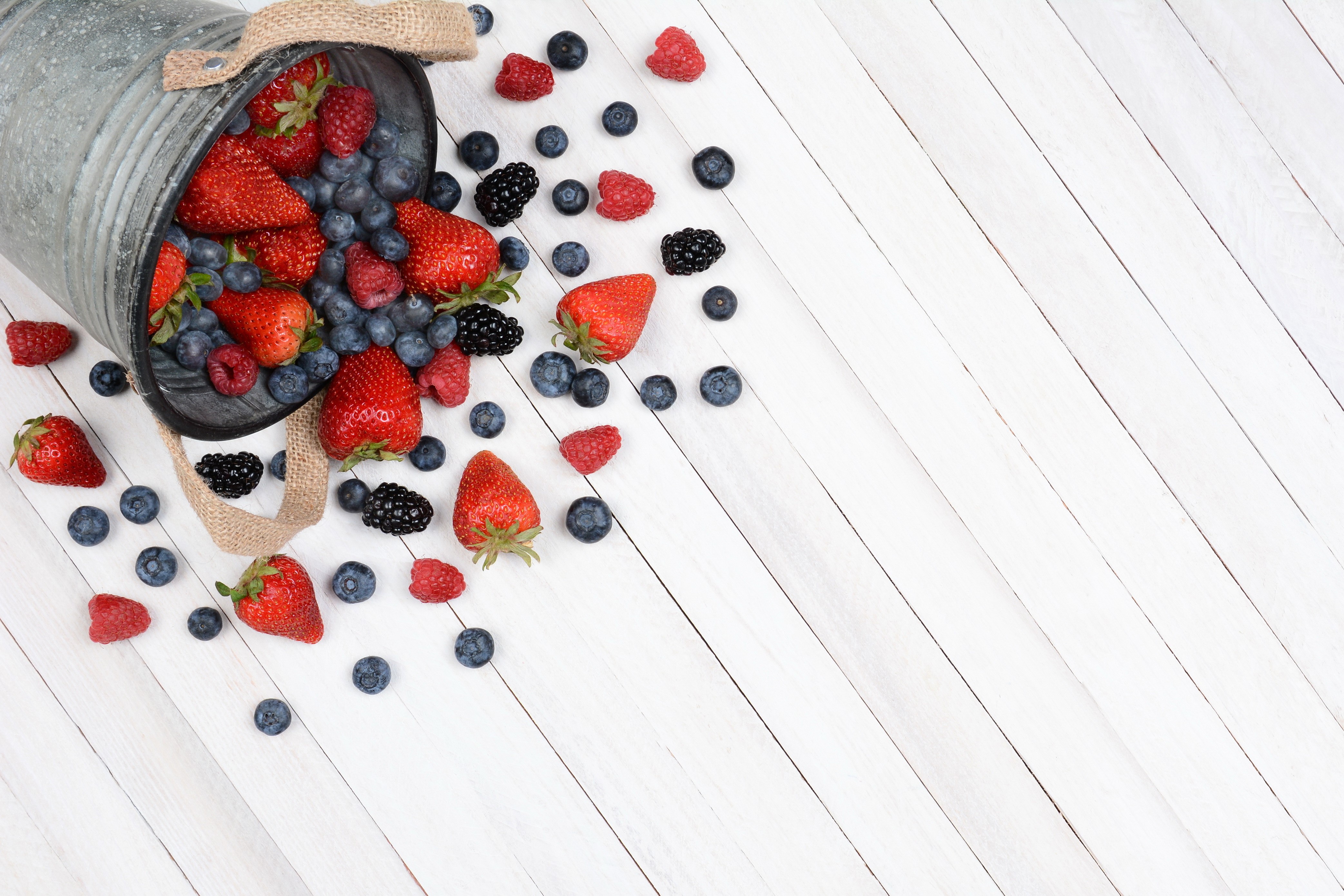 Berries spilling from a bucket onto wood planks HD Wallpaper