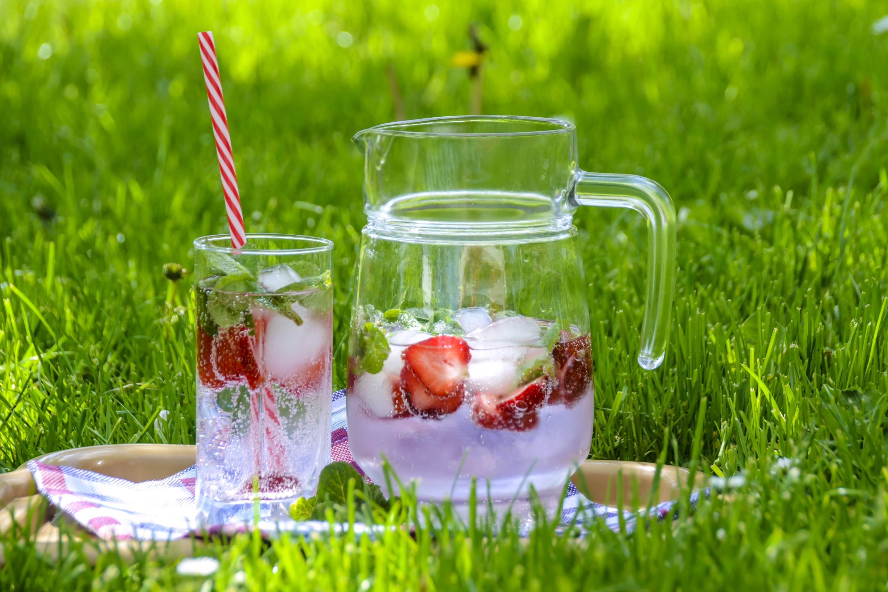 Strawberry mint infused water in a glass and pitcher on grass HD Wallpaper