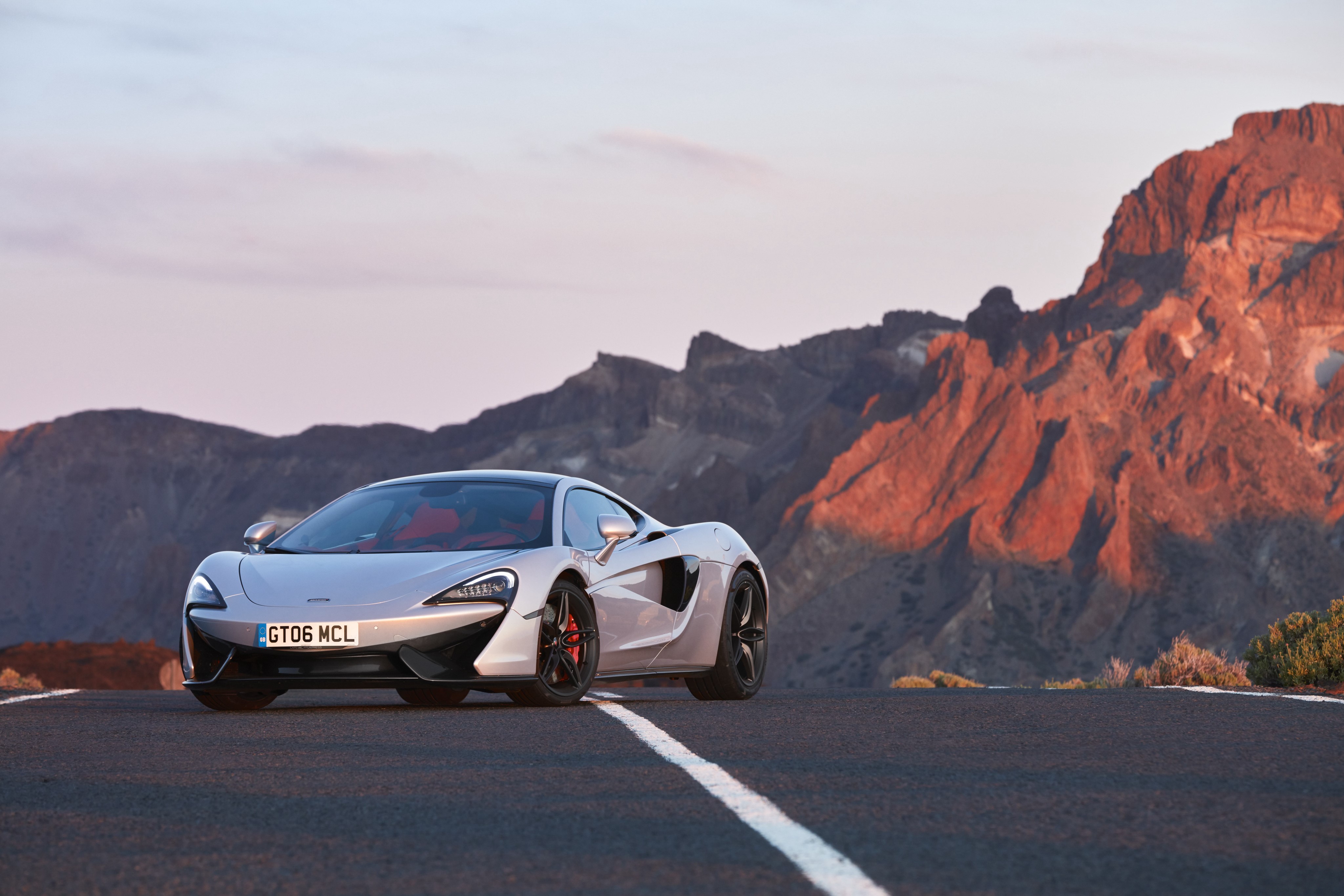 McLaren 570GT on a mountain road HD Wallpaper