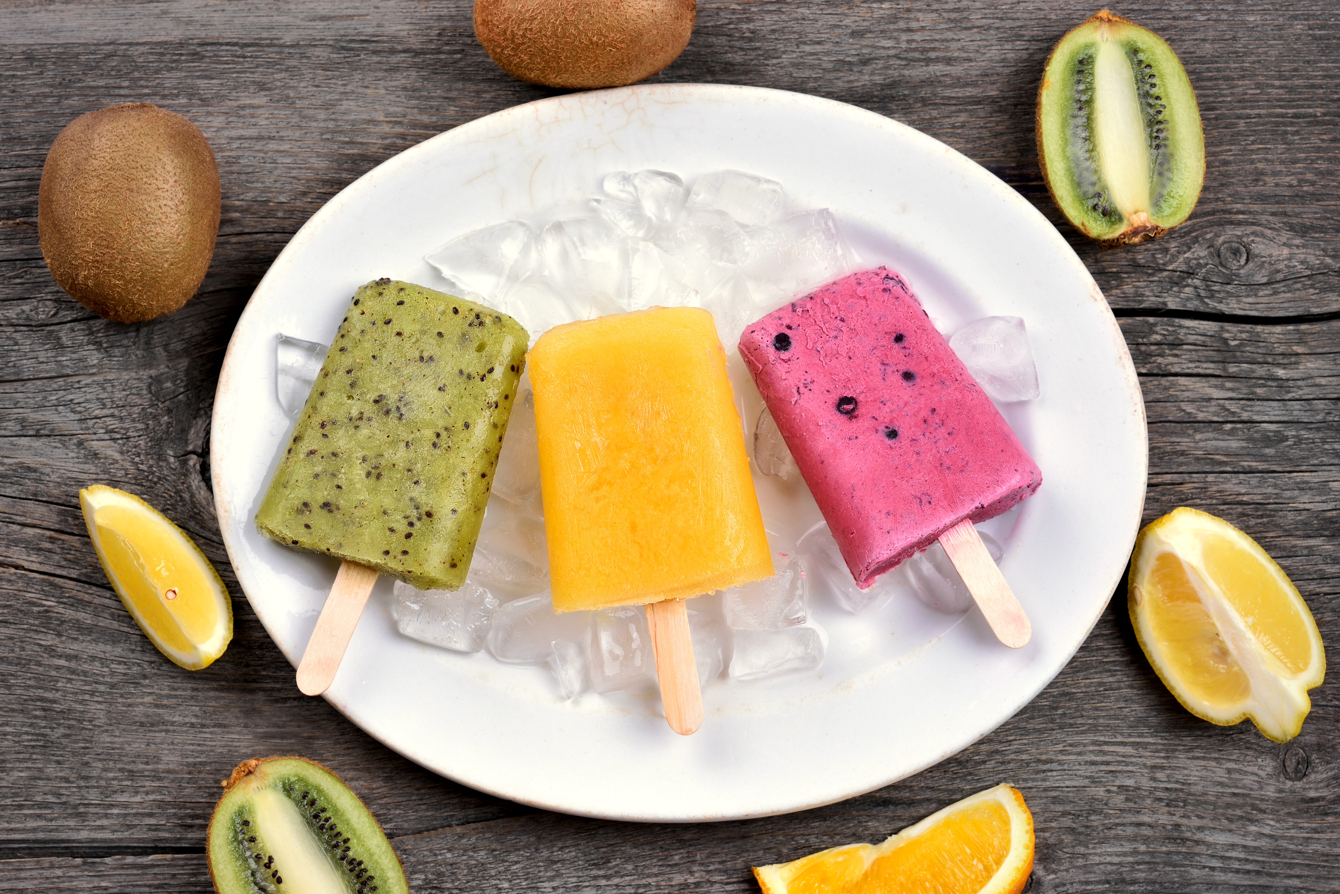 Three fruit popsicles on a plate with kiwi and orange slices HD Wallpaper