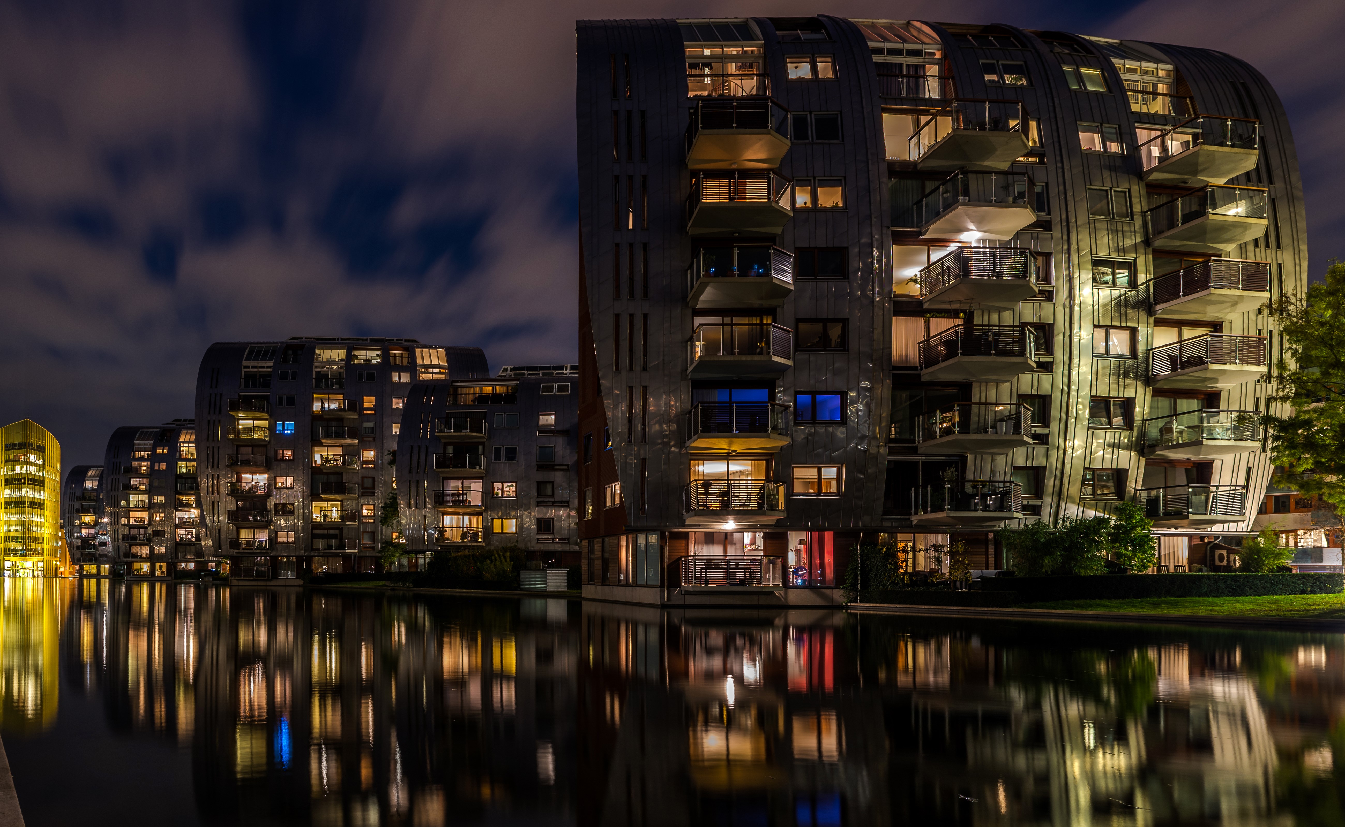 Modern apartment buildings at night reflected in a canal HD Wallpaper