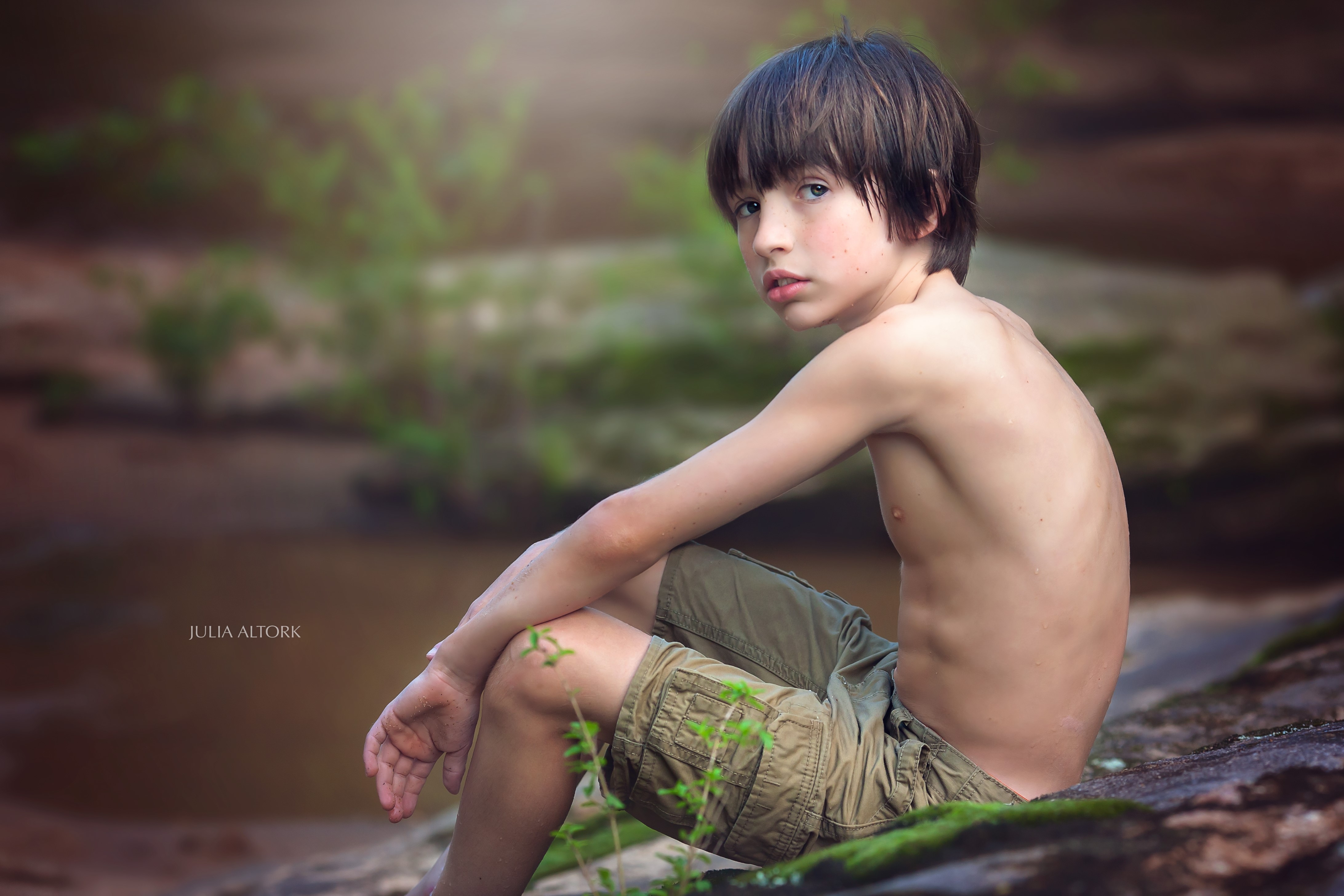 Boy sitting by a stream HD Wallpaper