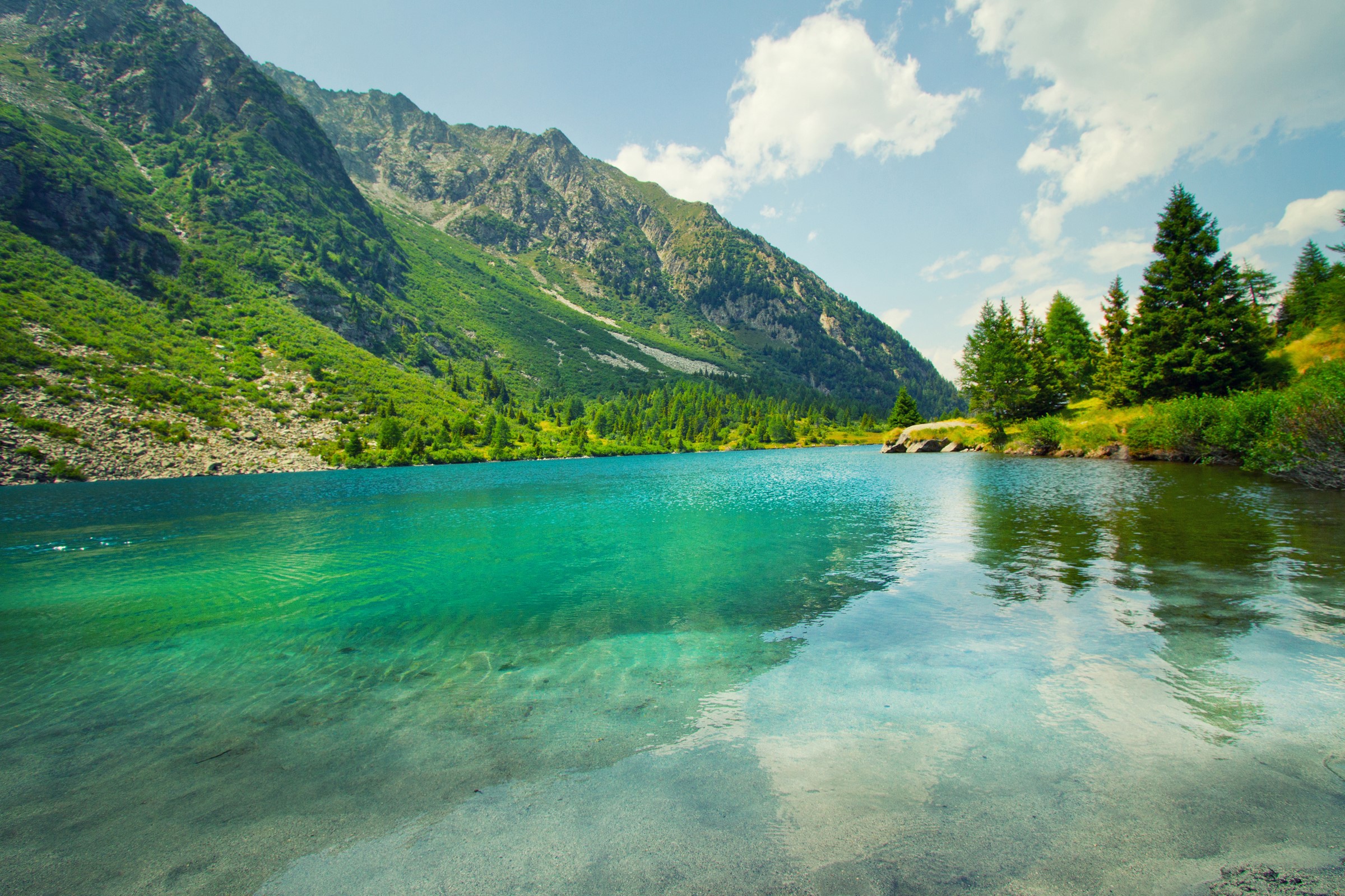 Turquoise mountain lake with green slopes and trees HD Wallpaper