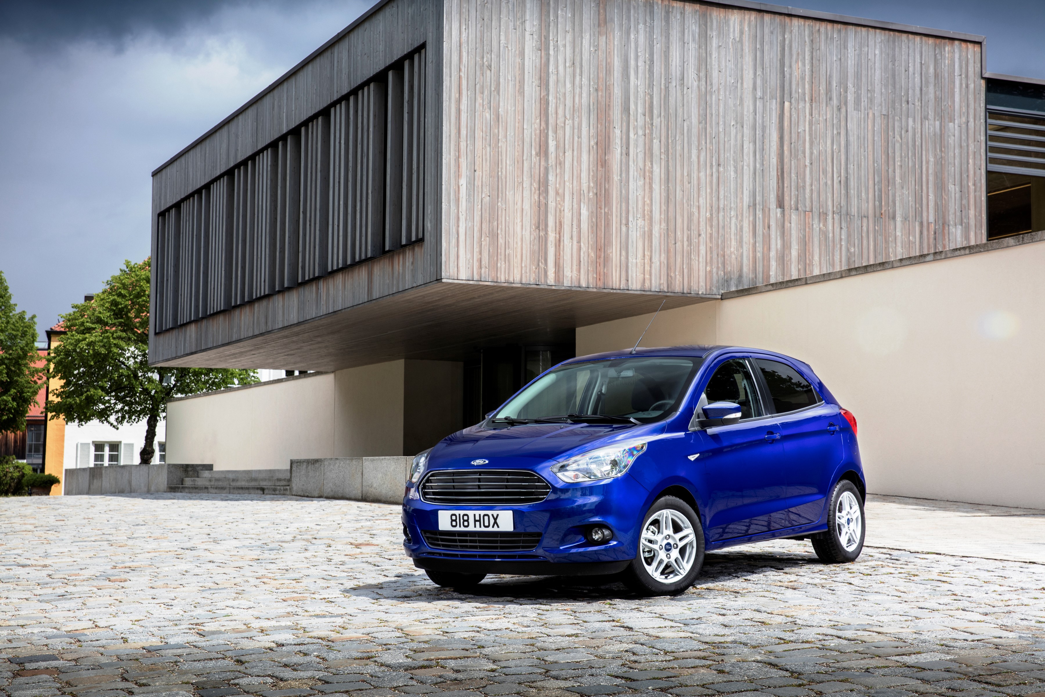 Blue Ford Ka parked in front of a modern building HD Wallpaper