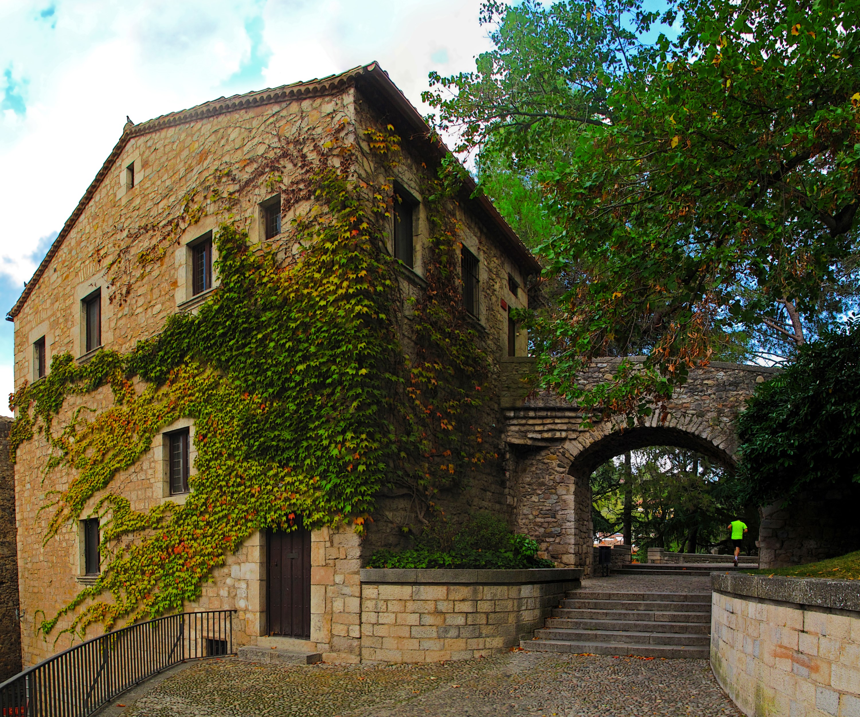 Stone building with ivy and arched walkway in Girona, Spain HD Wallpaper