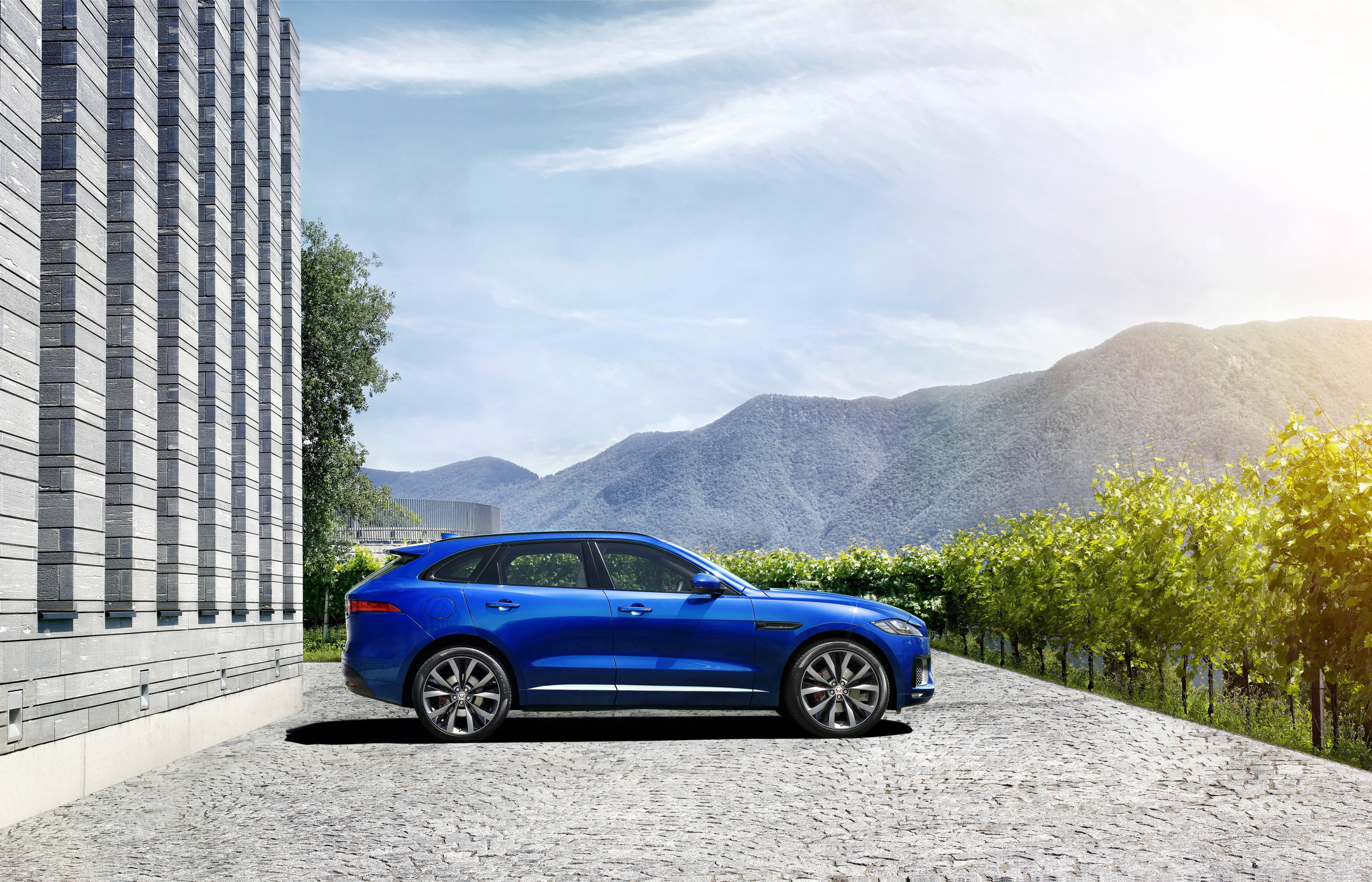 Blue Jaguar F-Pace SUV parked by modern building and vineyard HD Wallpaper