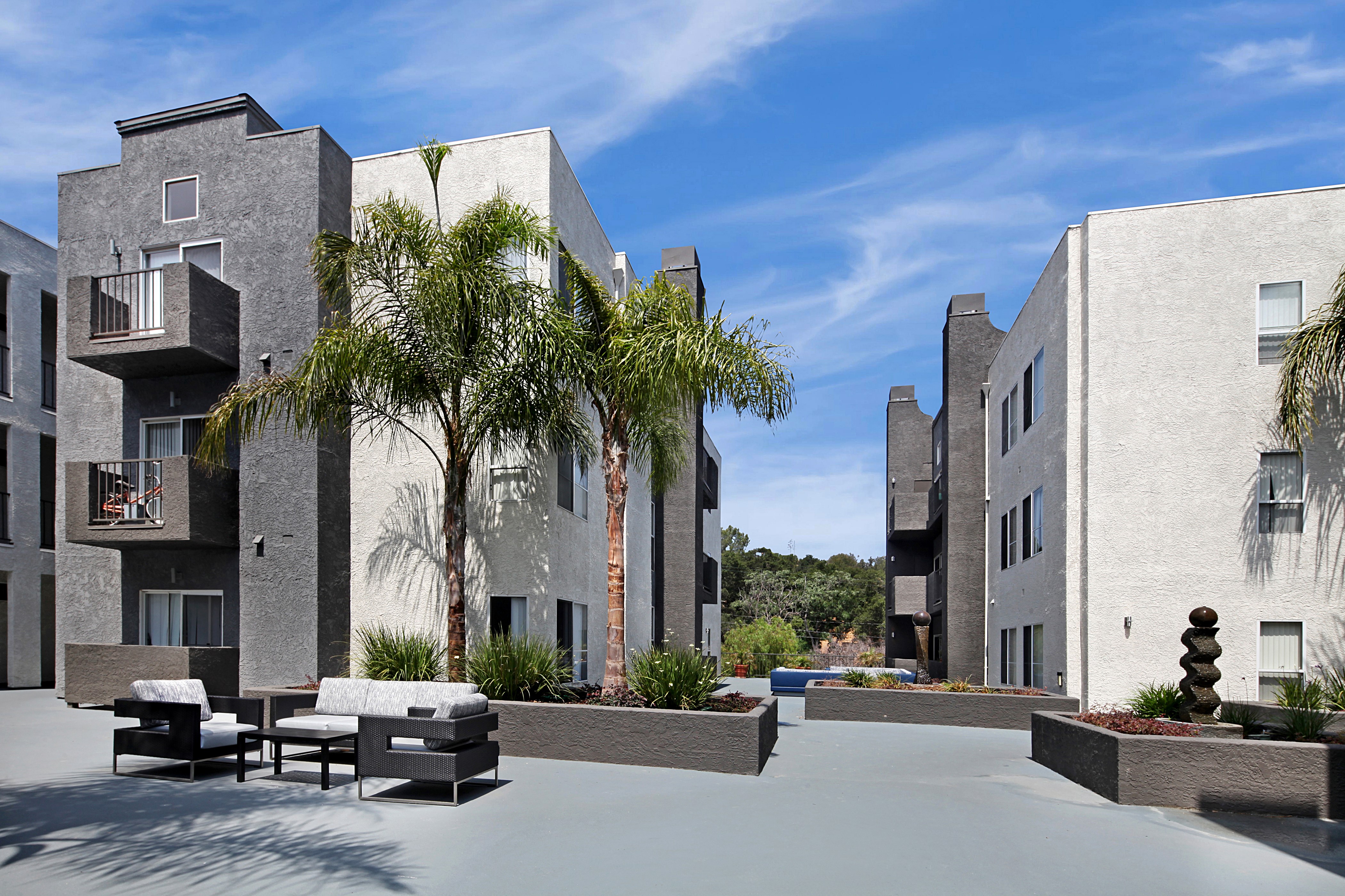 Apartment buildings with palm trees and outdoor seating HD Wallpaper