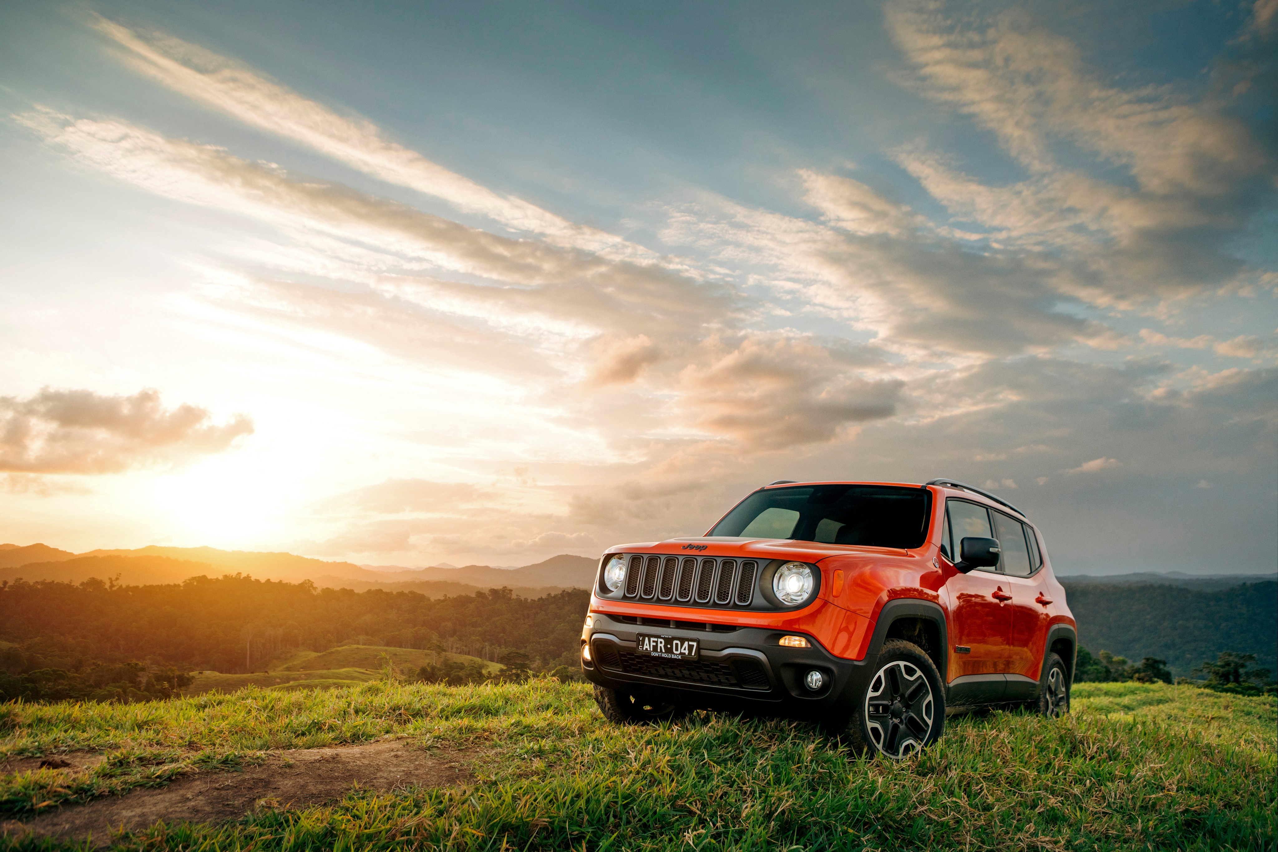 Orange Jeep Renegade on a grassy hill at sunset HD Wallpaper