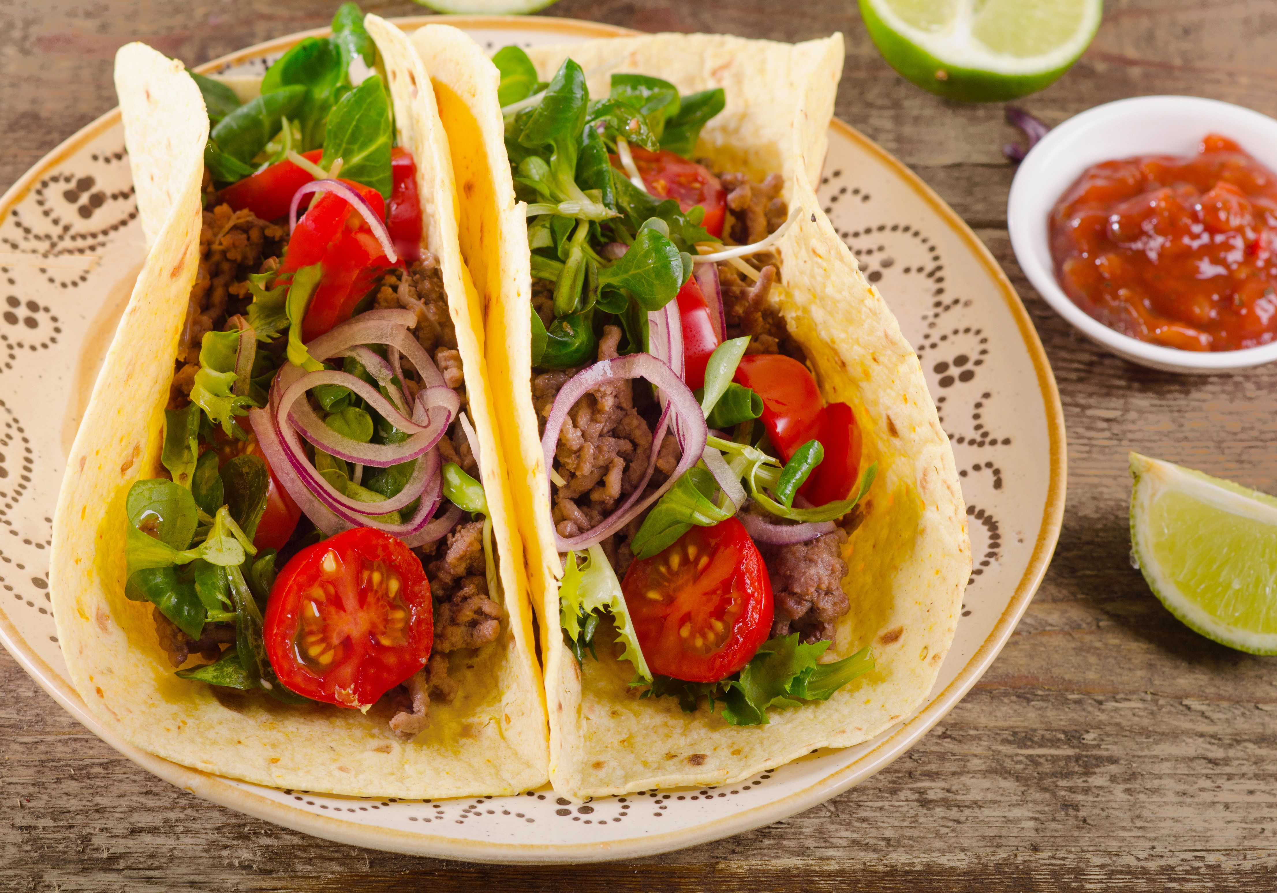 Two tacos with ground beef, lettuce, tomatoes, and onions HD Wallpaper