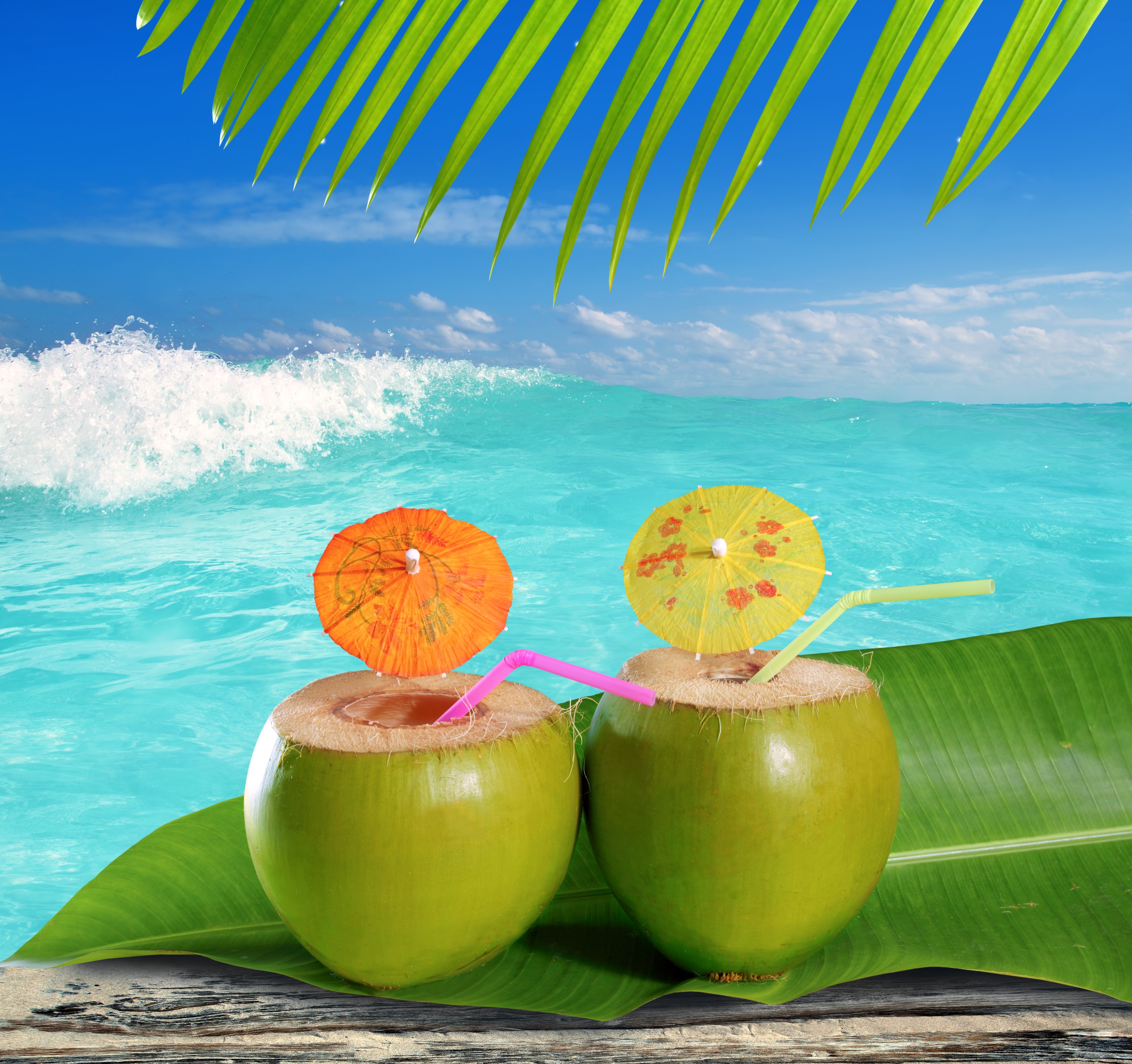 Two coconuts with cocktails on a beach HD Wallpaper