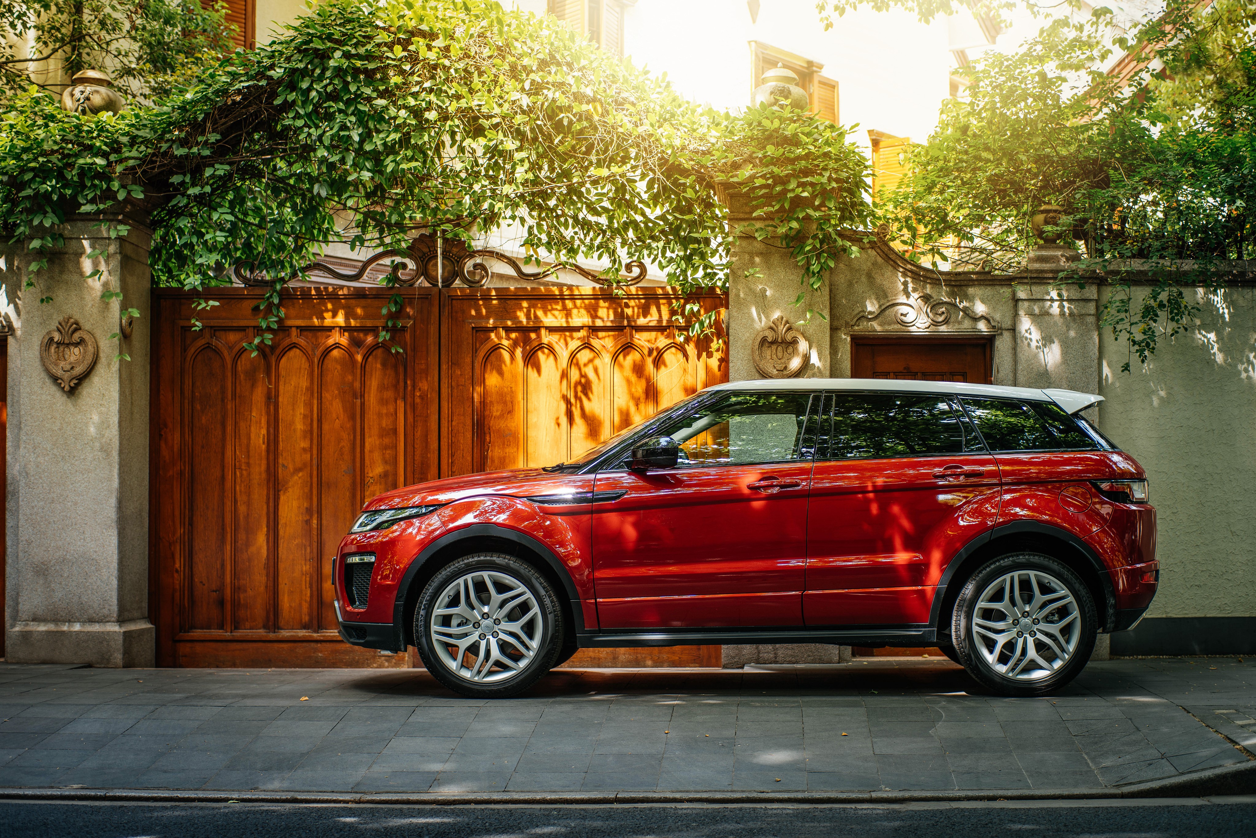 Red Land Rover Evoque parked by a wooden gate HD Wallpaper