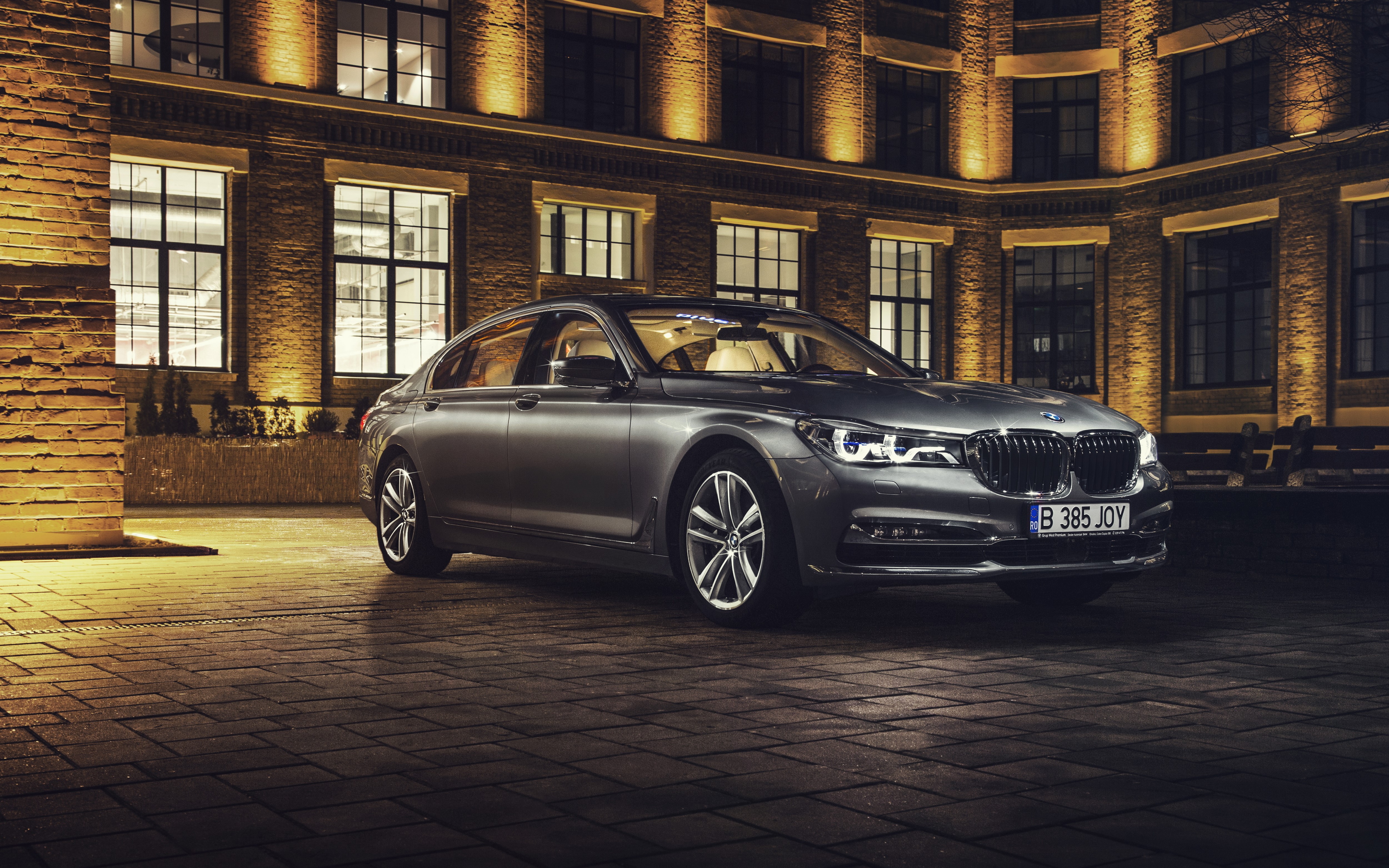 BMW 750Li parked in front of a brick building at night HD Wallpaper