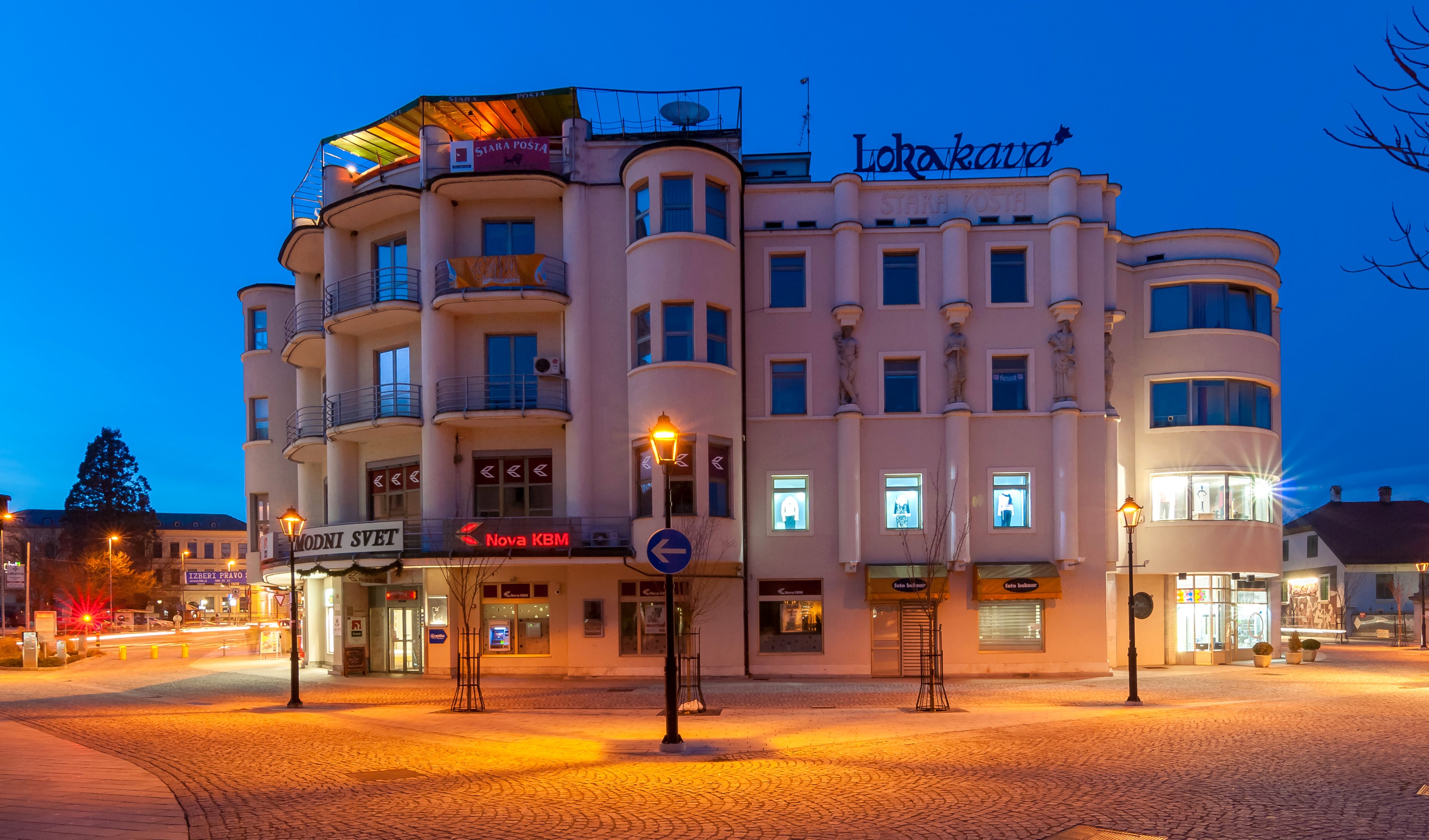 Building with "Lokakava" sign and street lights at dusk HD Wallpaper