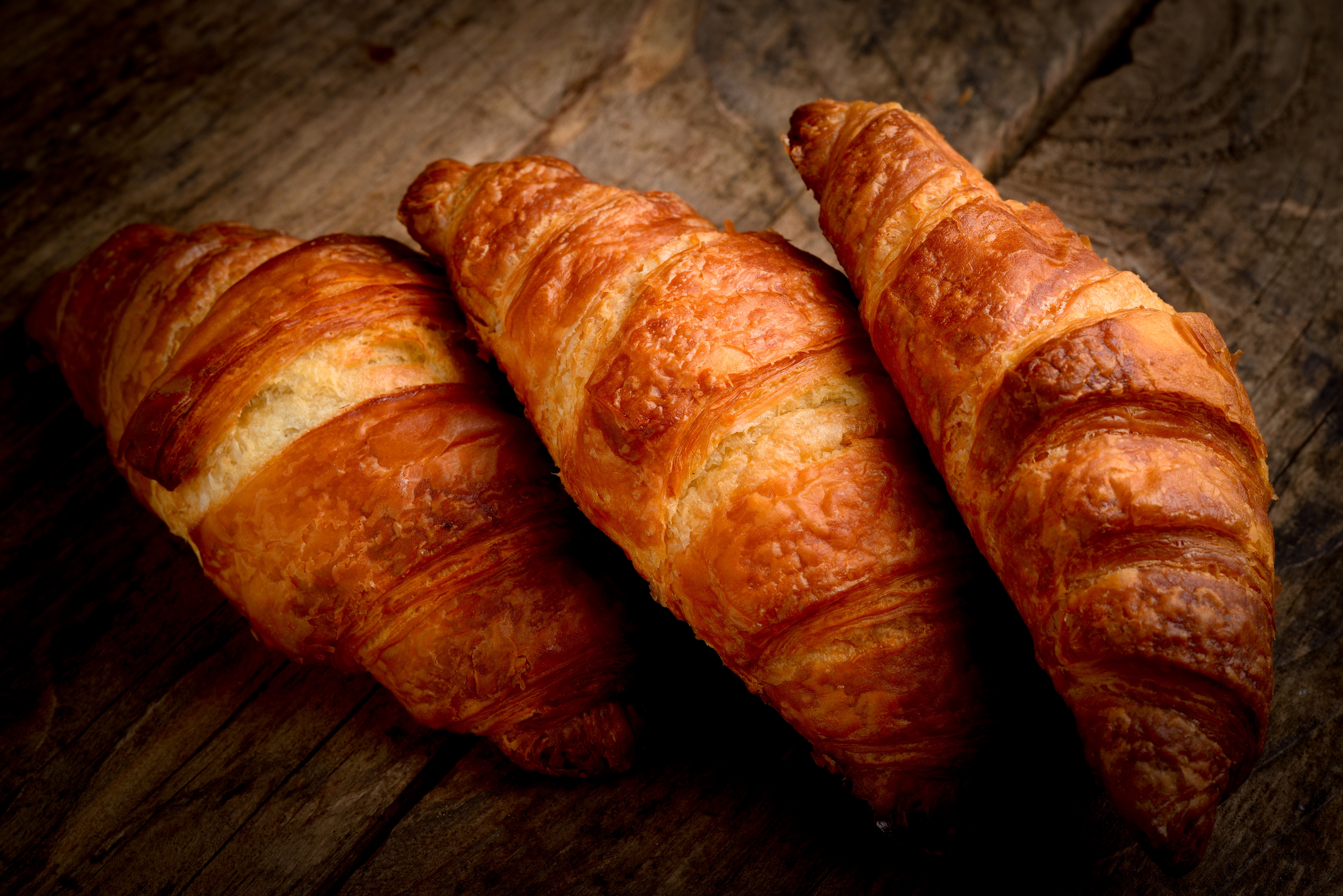Three Croissants on a Wooden Surface HD Wallpaper