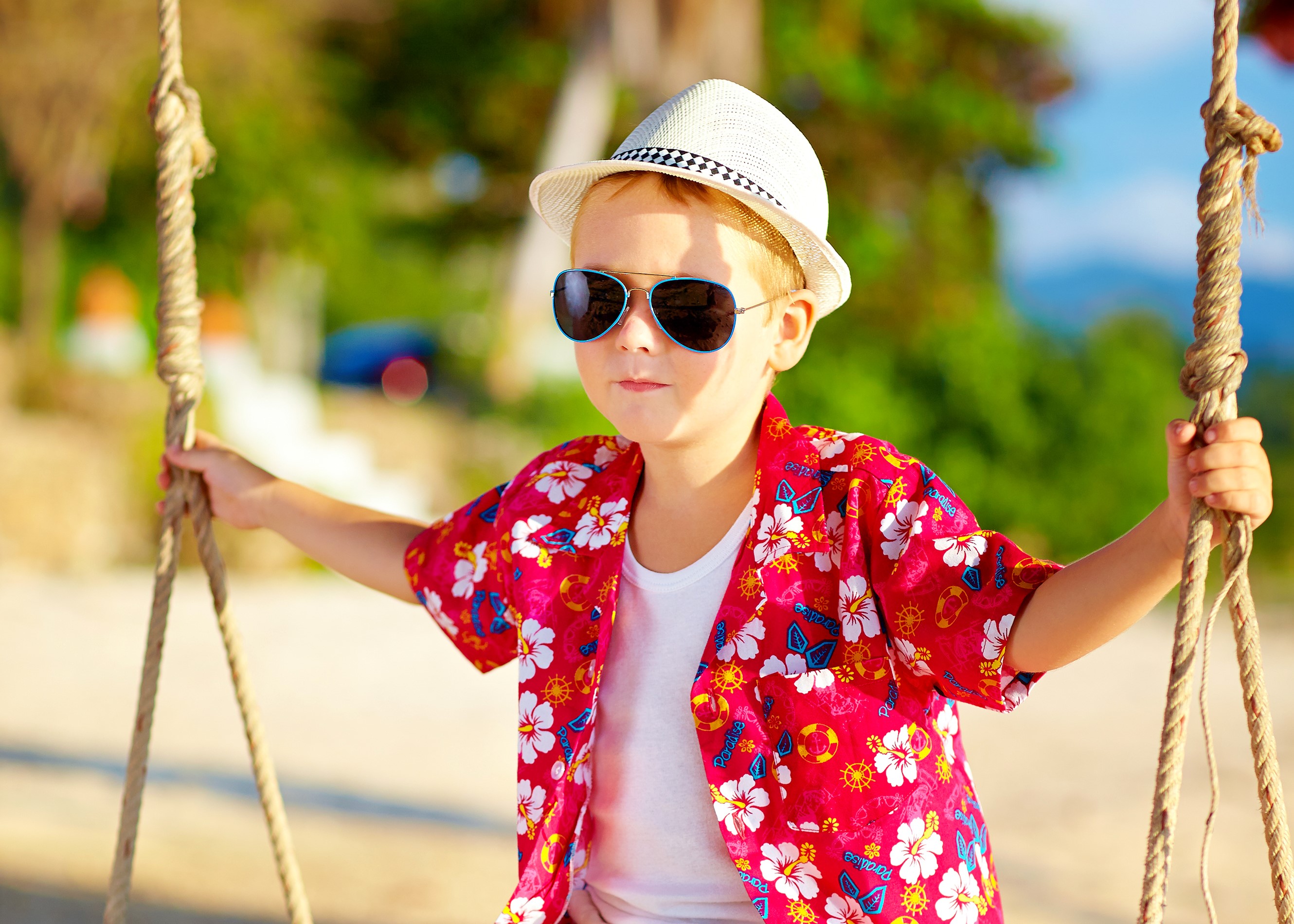 Boy in Hawaiian shirt and hat on a swing HD Wallpaper