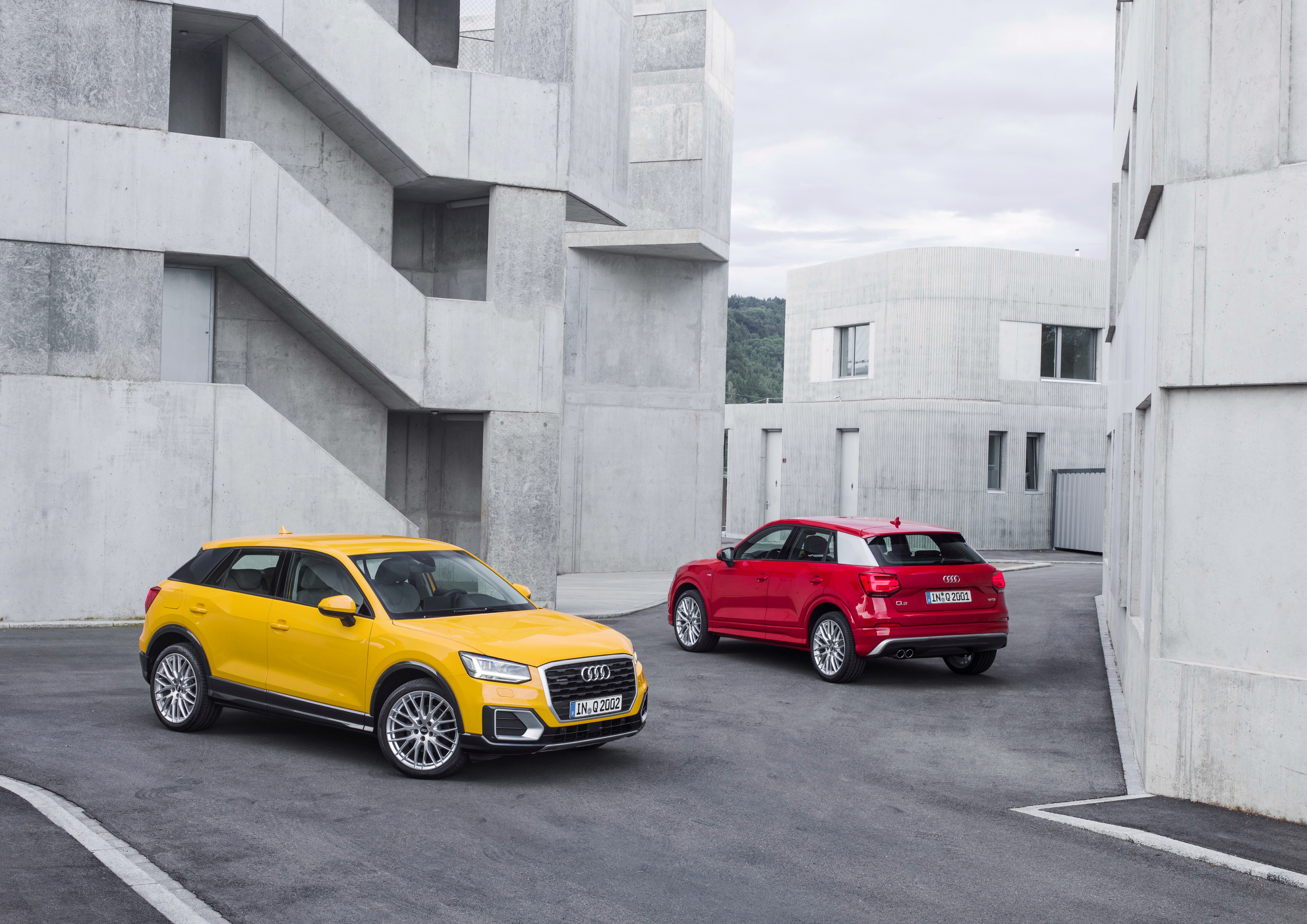 Two Audi Q2 cars in a modern architectural setting HD Wallpaper