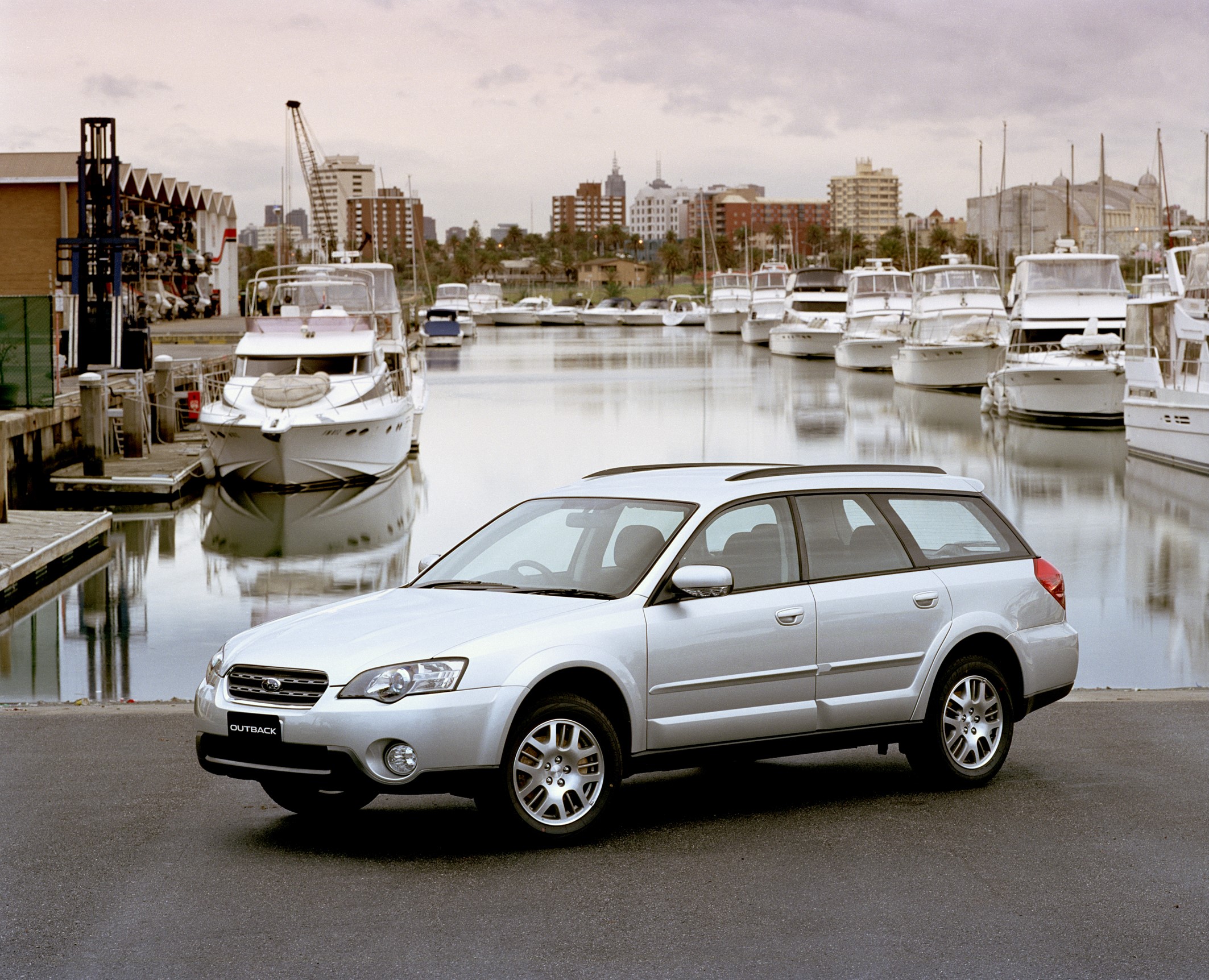 Silver Subaru Outback wagon parked by a marina HD Wallpaper