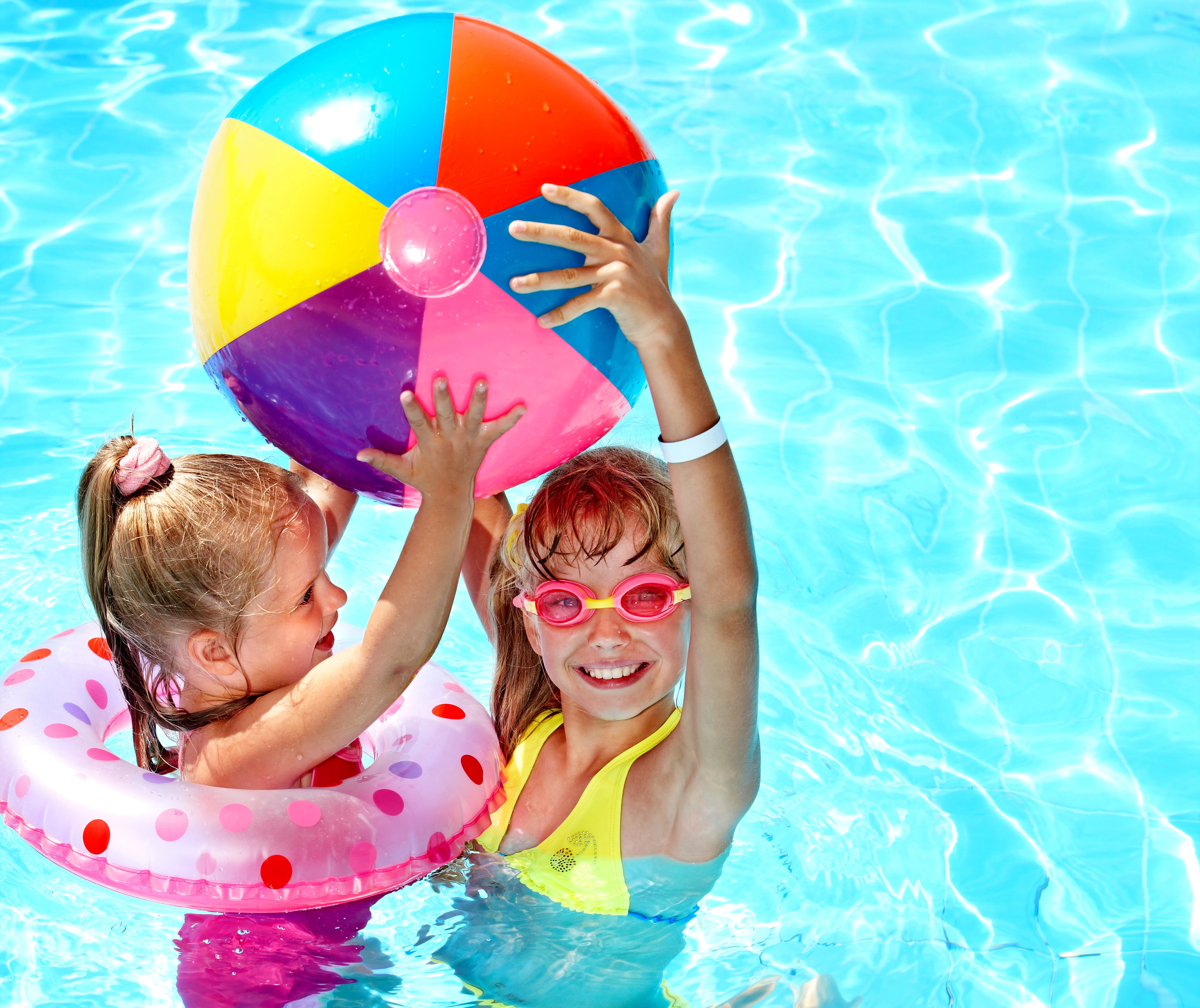 Two little girls playing with a beach ball in a pool HD Wallpaper