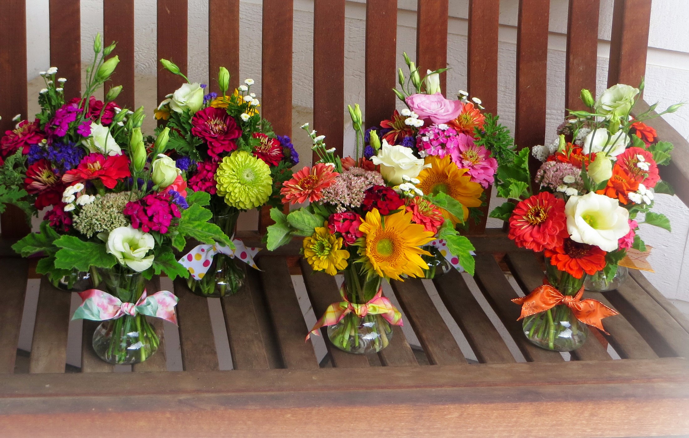 Assorted flower bouquets in glass vases on a wooden bench HD Wallpaper