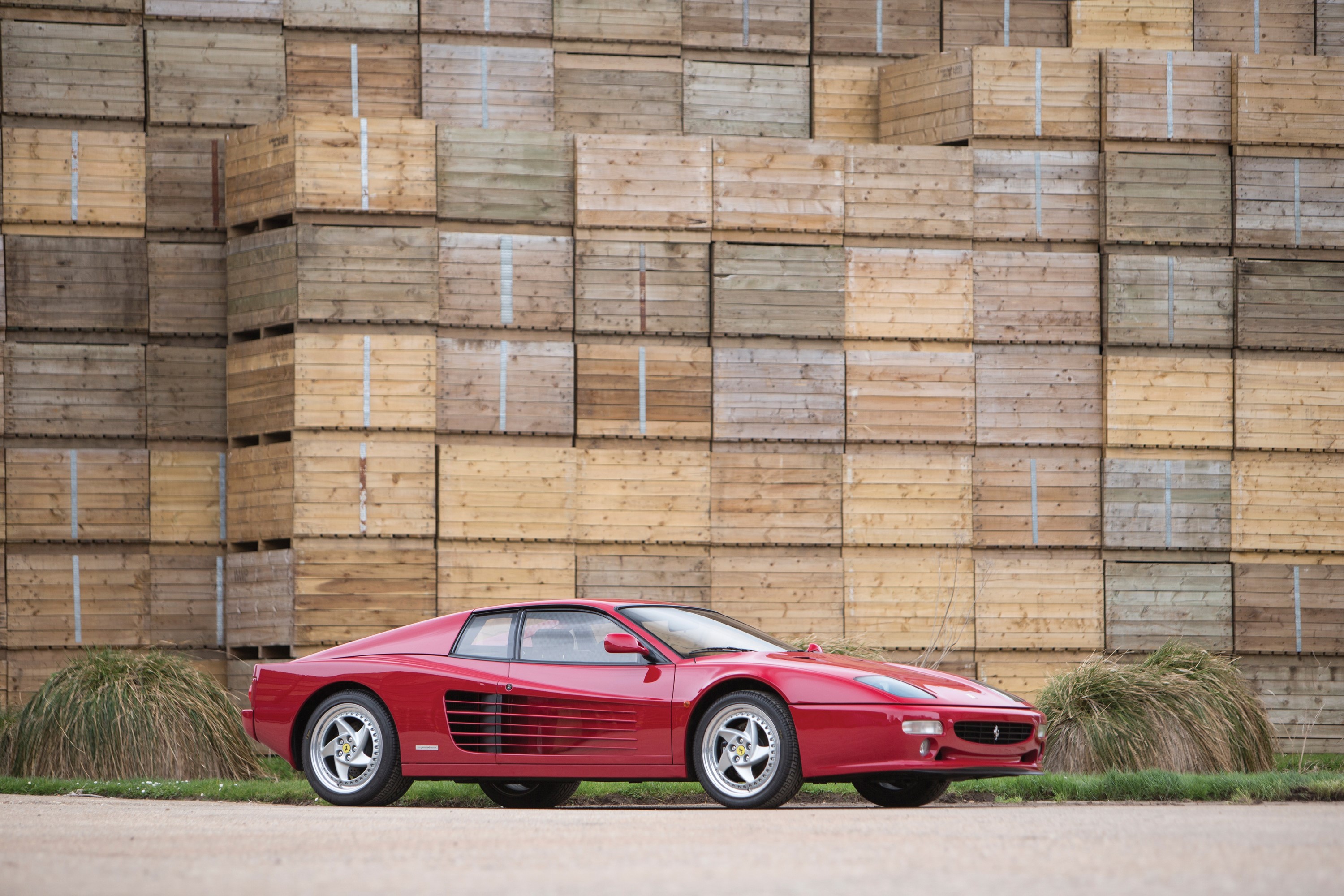 Red Ferrari F512 M parked in front of wooden crates HD Wallpaper