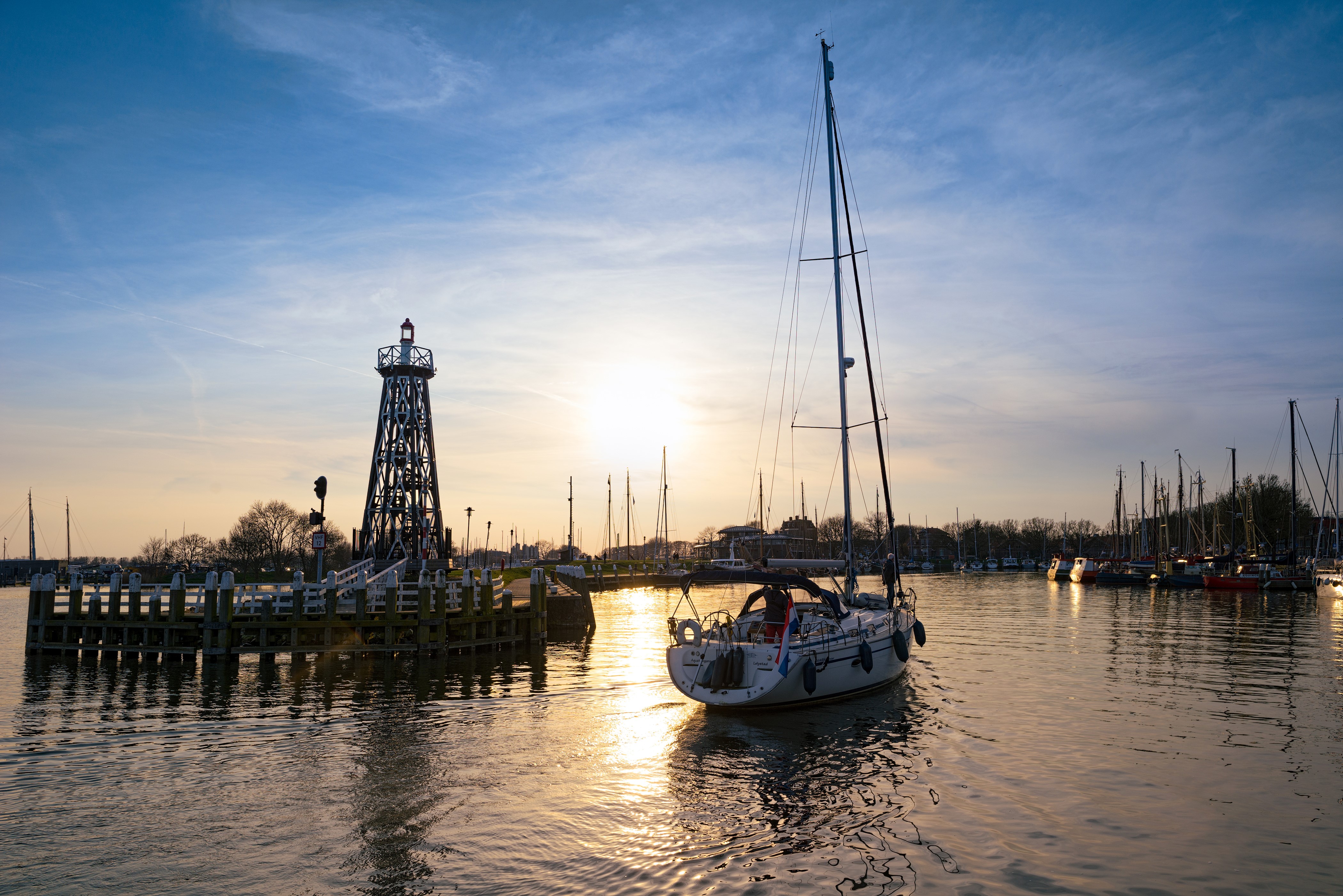 Sailboat and lighthouse in Enkhuizen harbor at sunset HD Wallpaper