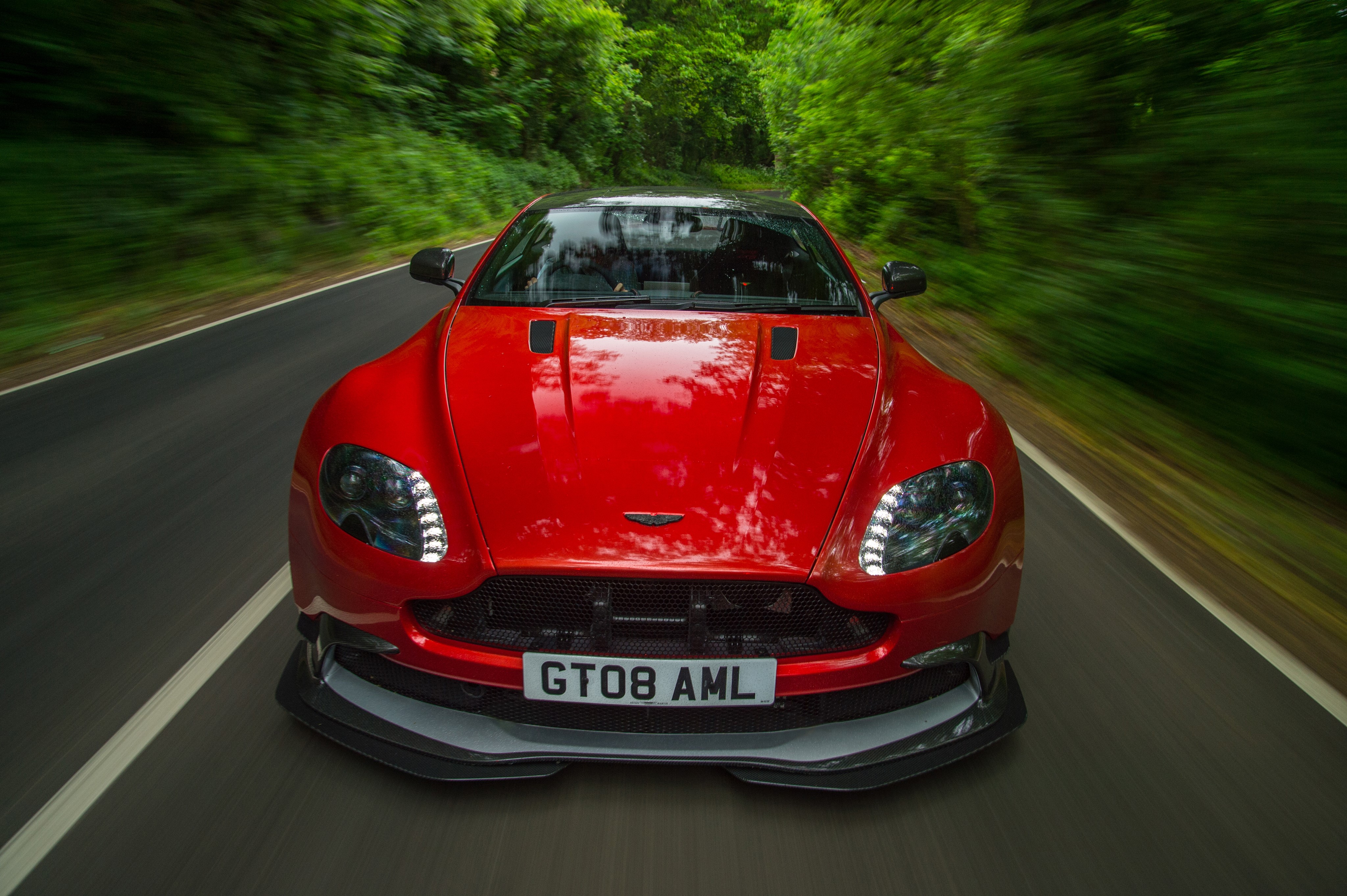 Red Aston Martin Vantage driving on a road HD Wallpaper