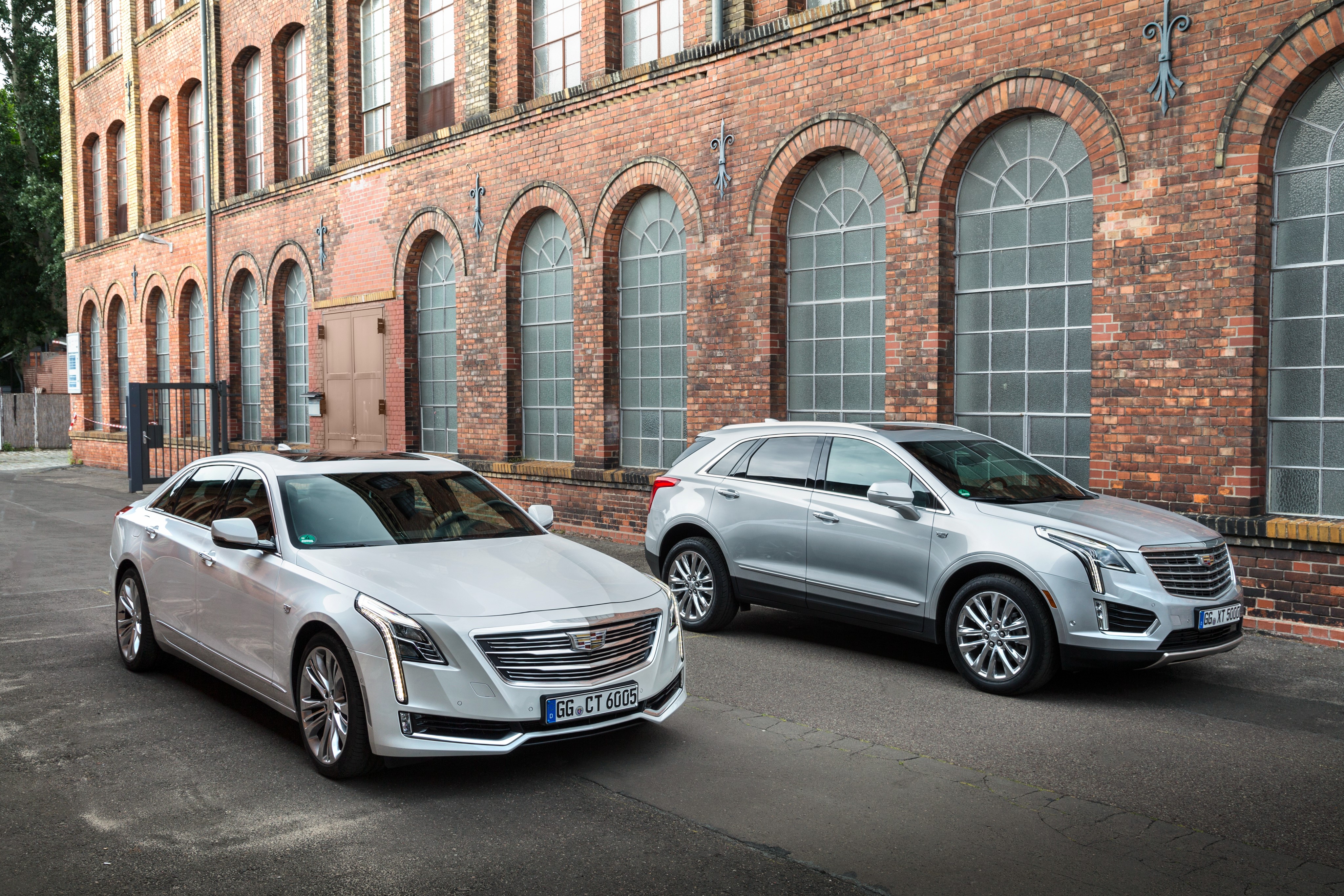Cadillac CT6 and XT5 parked in front of brick building HD Wallpaper