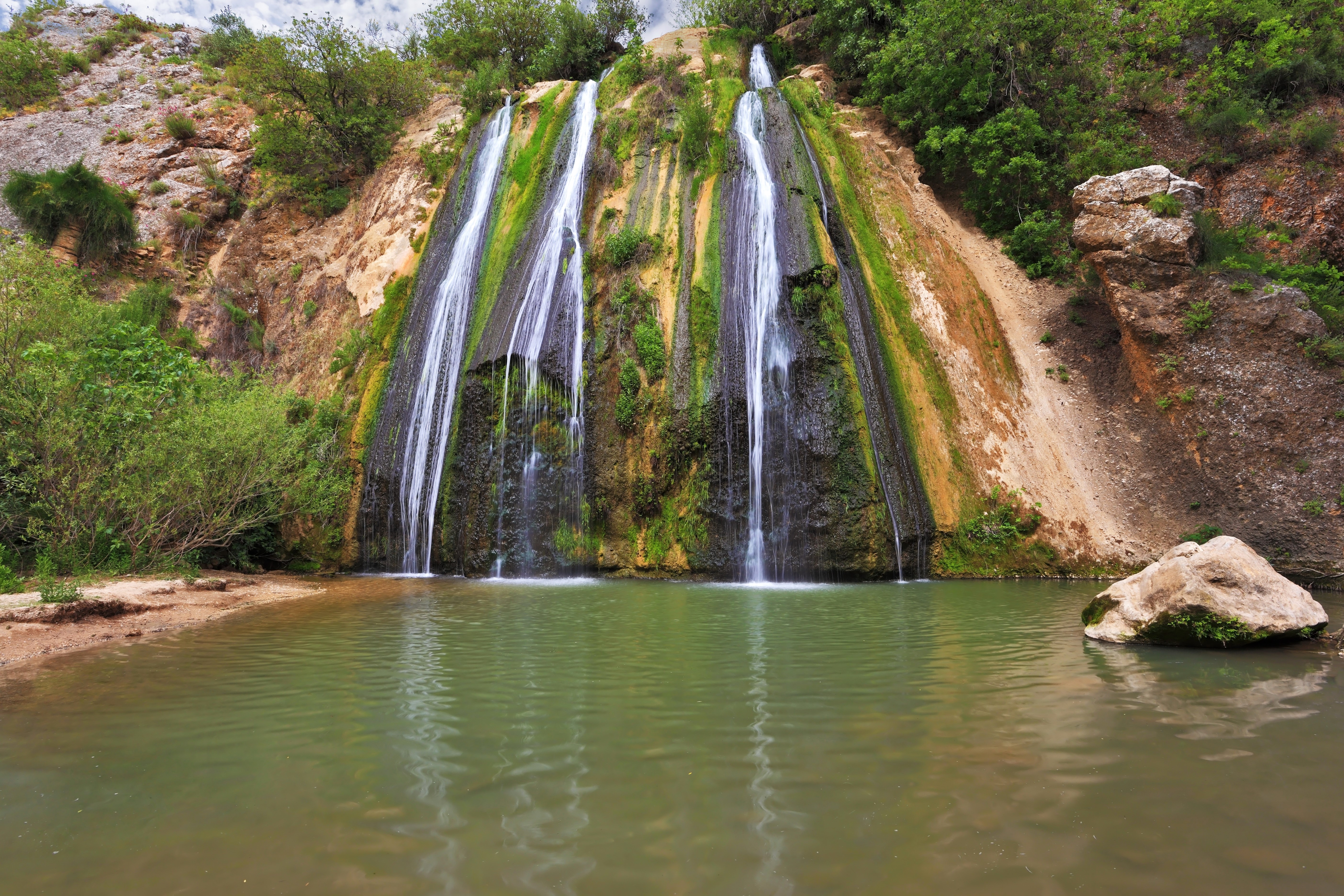 Waterfalls cascading over mossy rocks into a pool HD Wallpaper