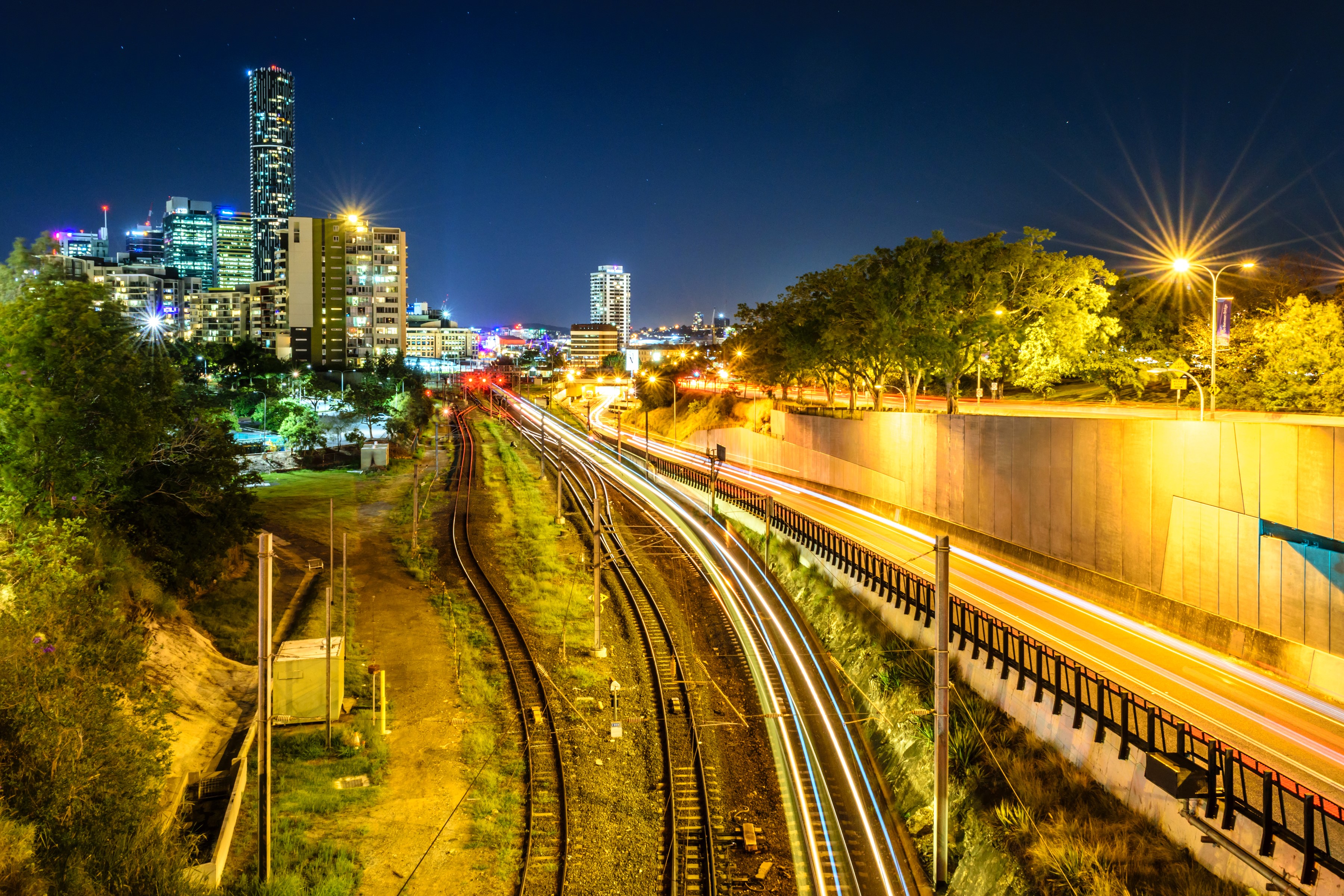 Brisbane city skyline at night with train tracks and highway HD Wallpaper