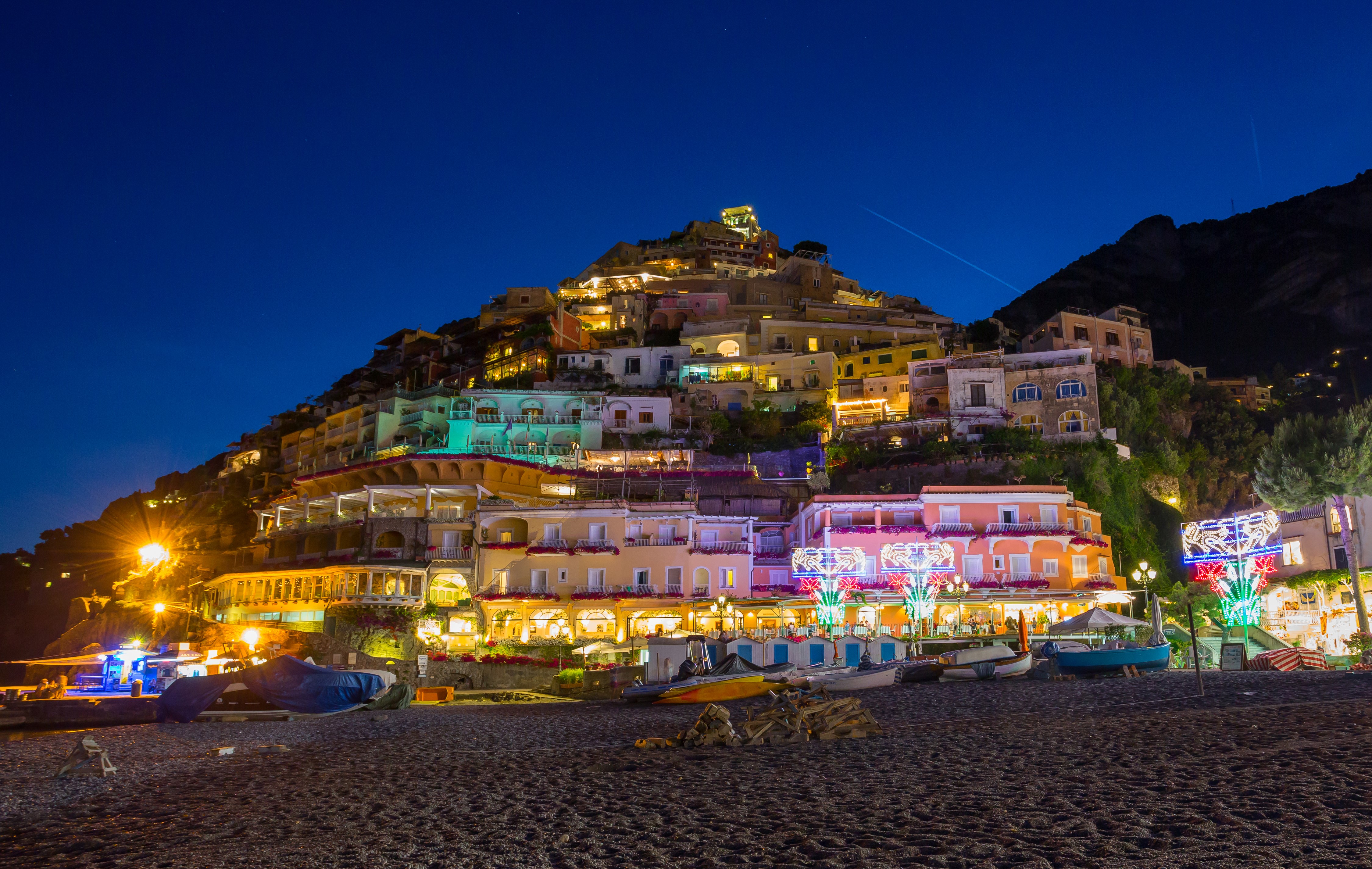 Positano at night with illuminated houses and boats on the beach HD Wallpaper