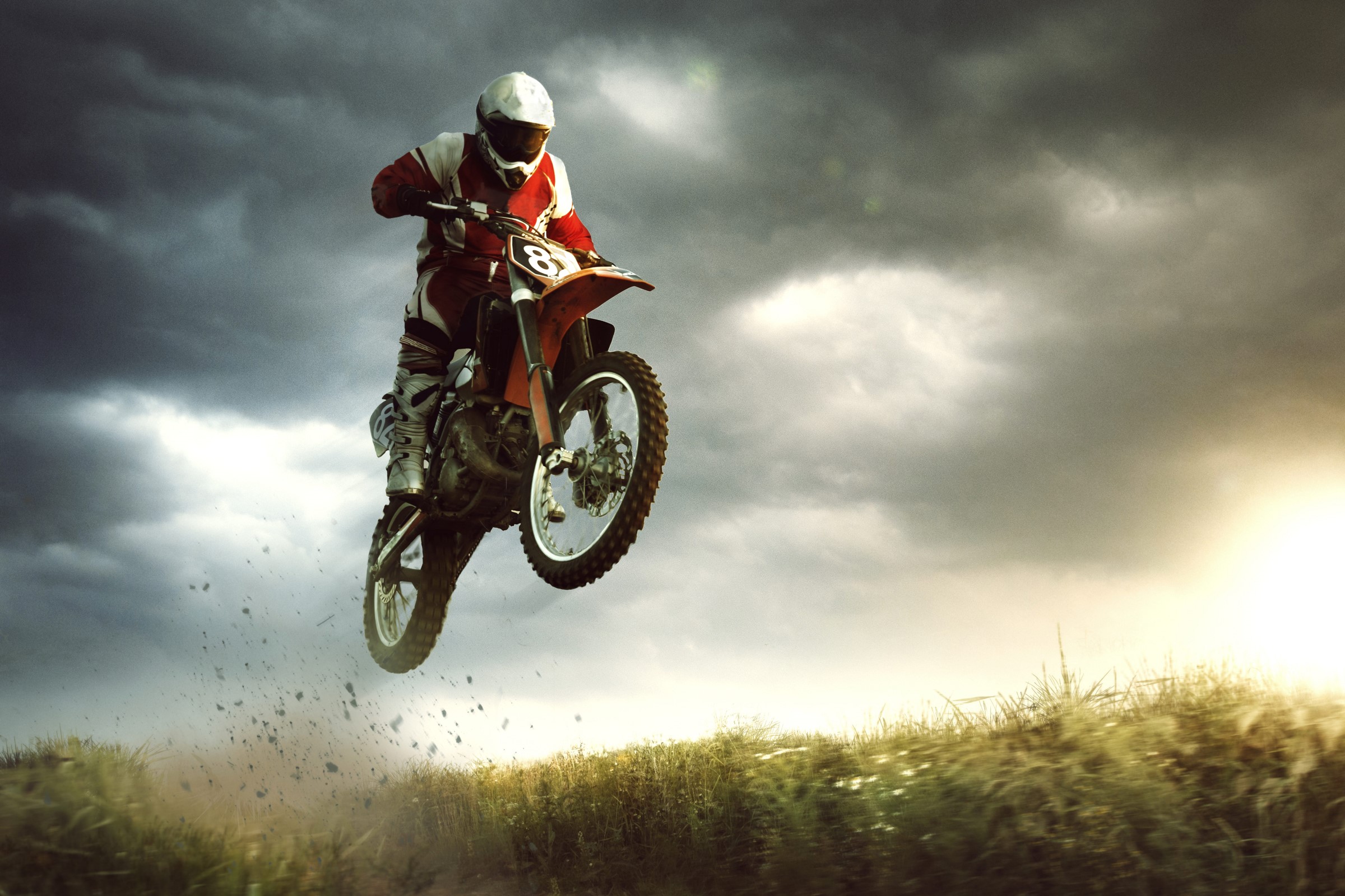 Motocross rider in mid-air jump against stormy sky HD Wallpaper