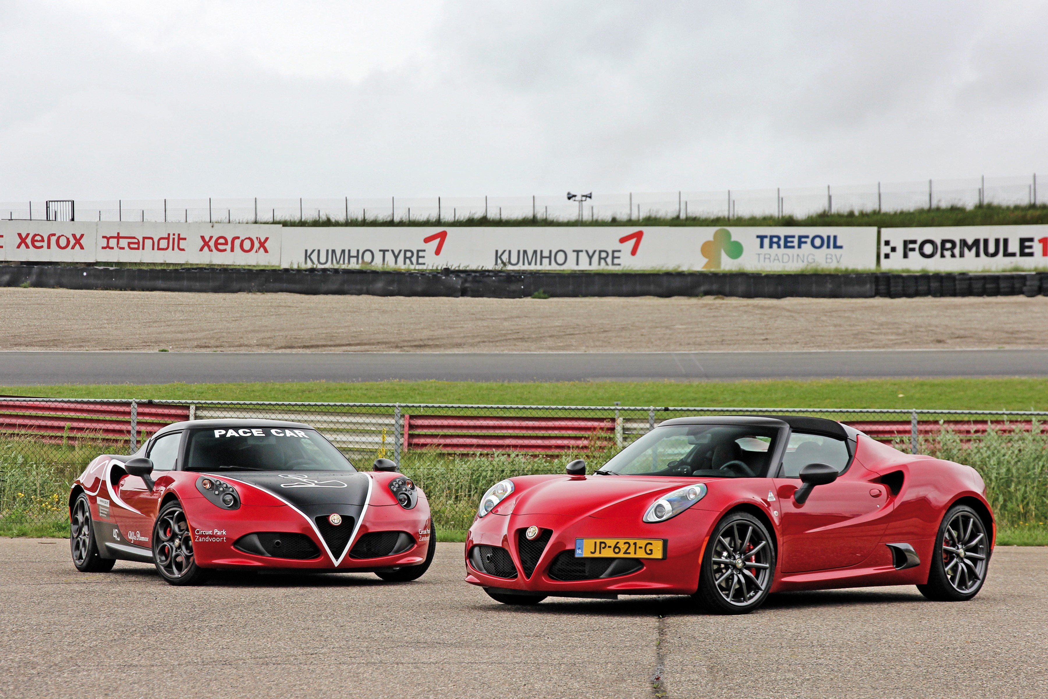 Two red Alfa Romeo 4C Spider cars on a race track HD Wallpaper