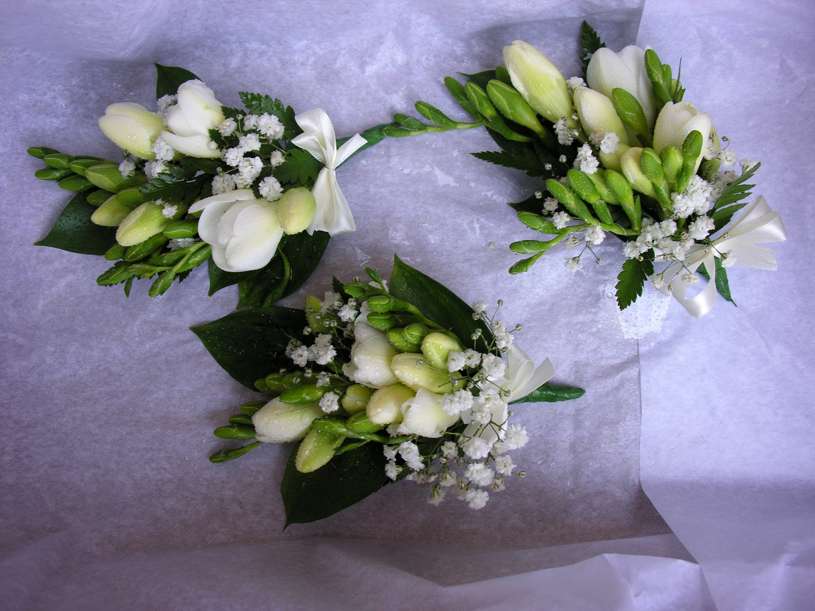 Three white freesia bouquets with green leaves and baby's breath HD Wallpaper