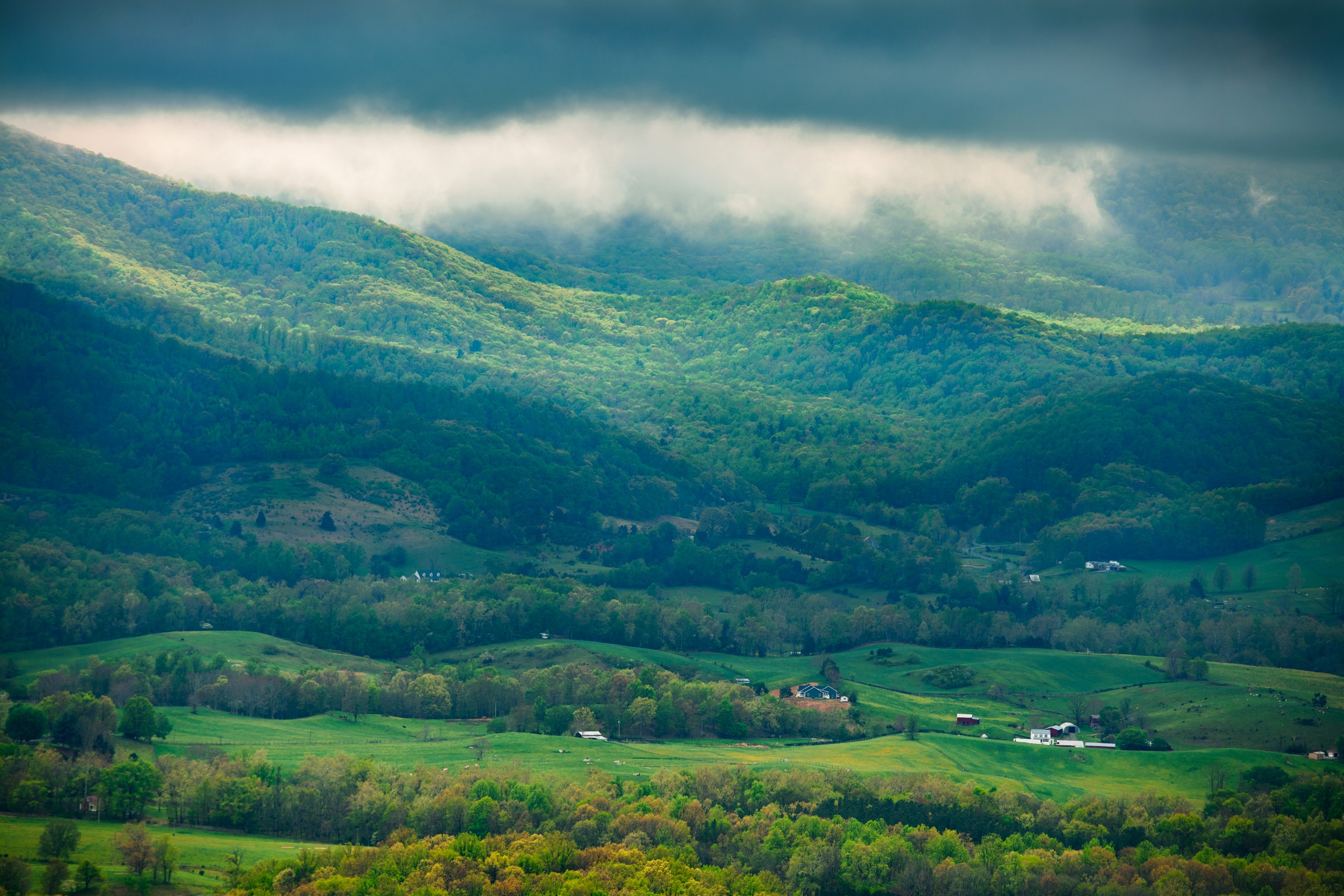 Rolling green hills and mountains under cloudy sky HD Wallpaper