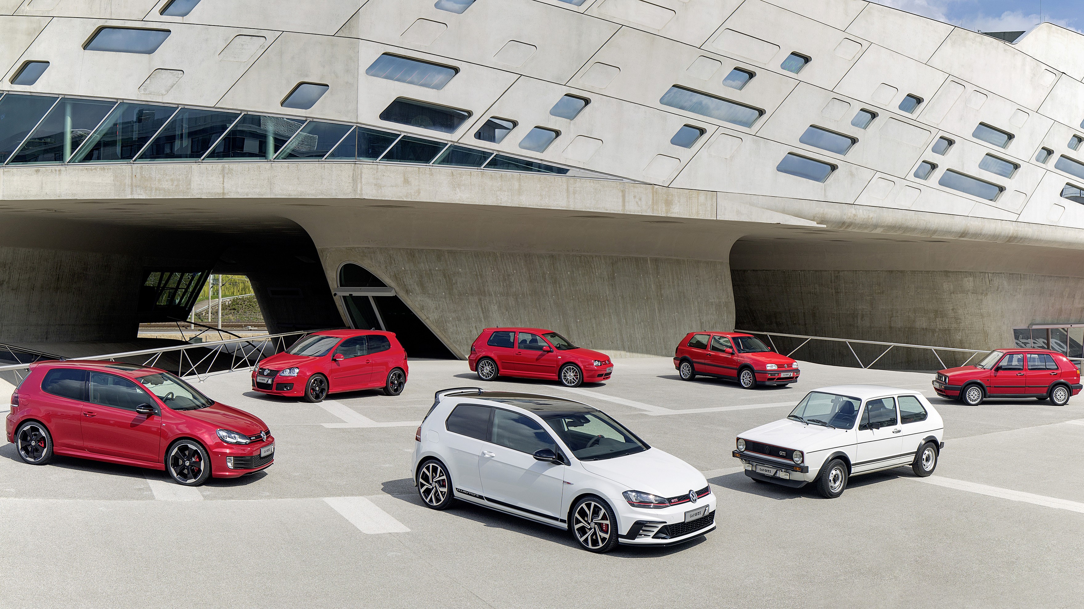 Volkswagen Golf cars lined up outside modern building HD Wallpaper