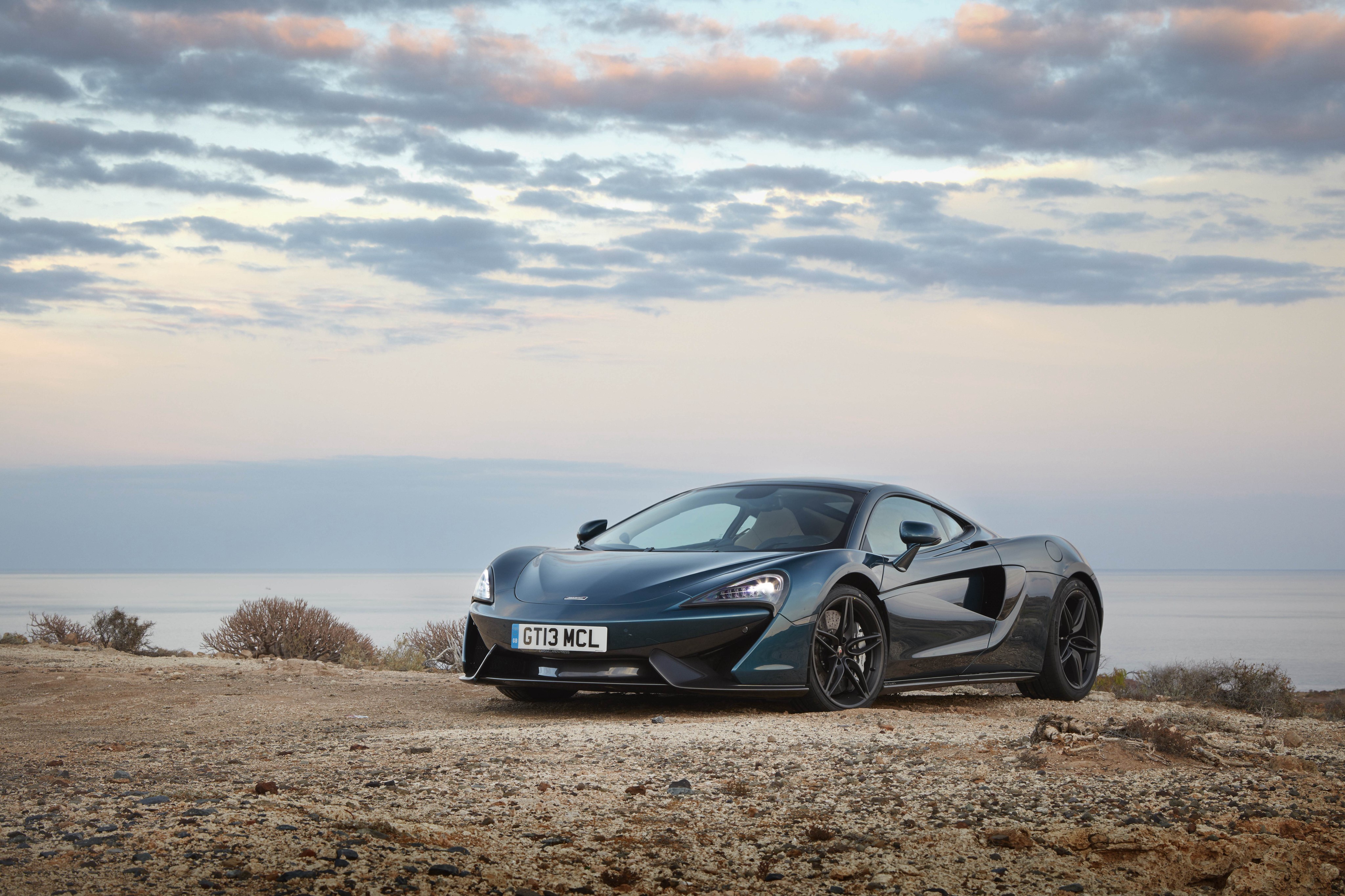 McLaren 570GT on a rocky coast HD Wallpaper