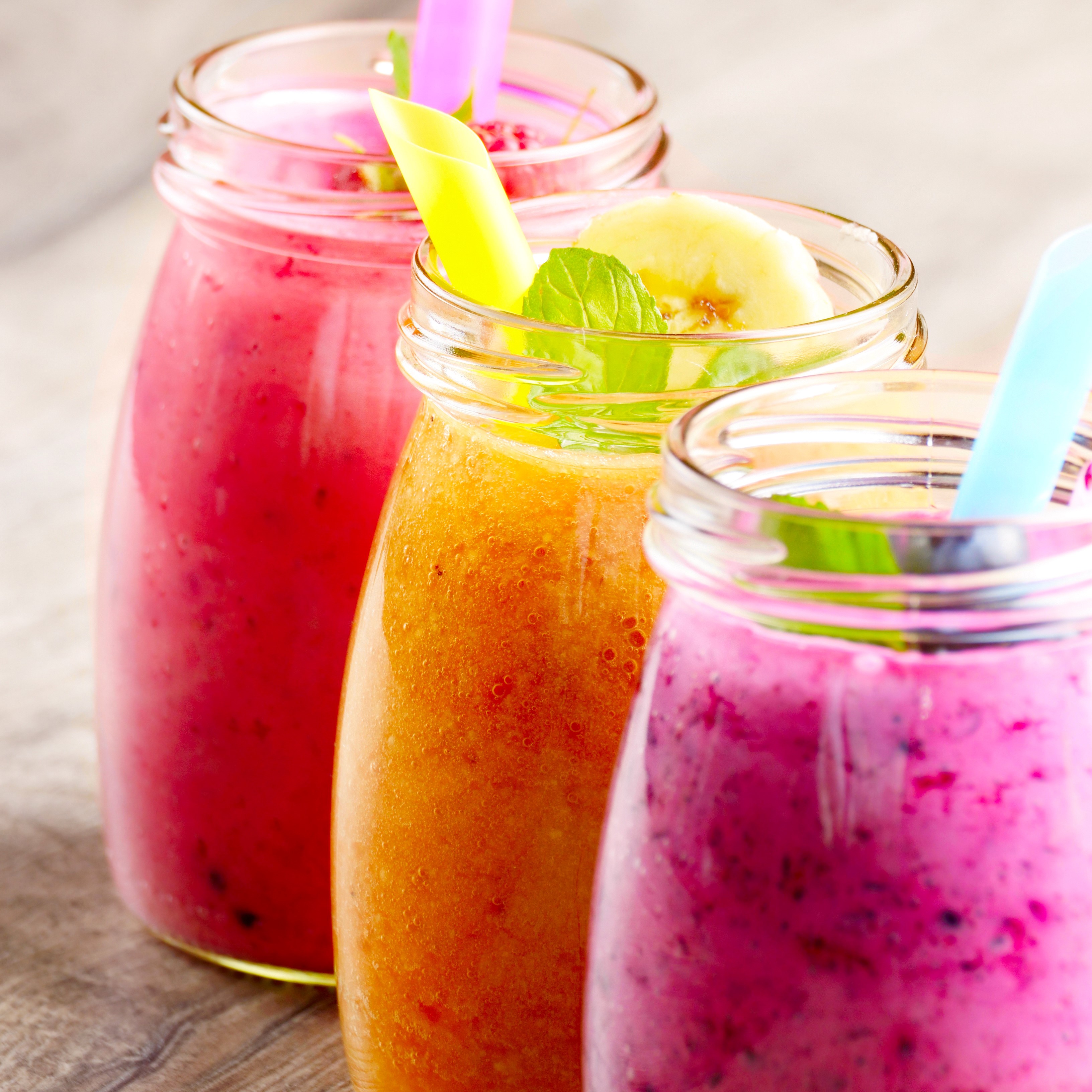 Three colorful smoothies in glass jars with straws HD Wallpaper