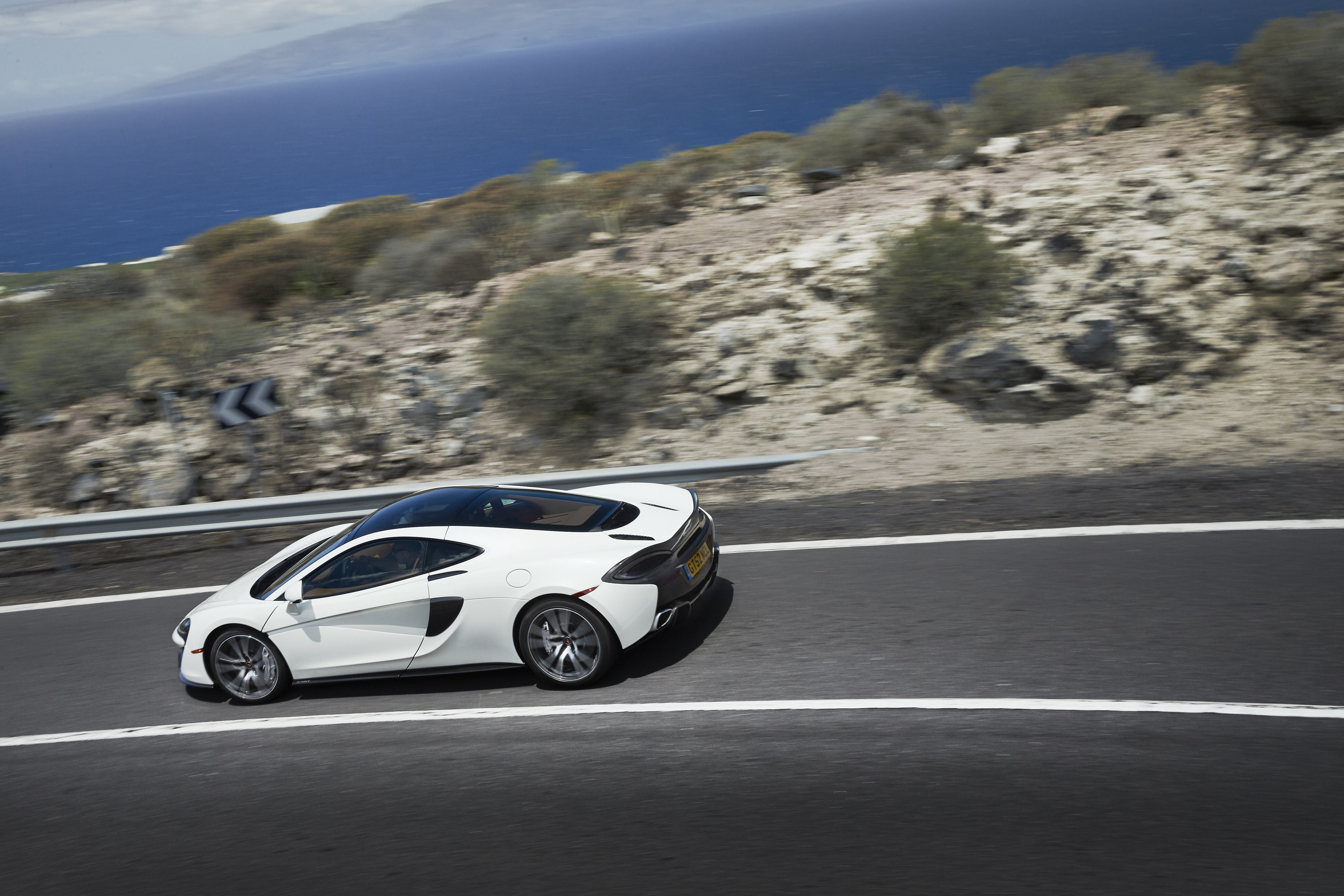 White McLaren 570GT on a Coastal Road HD Wallpaper
