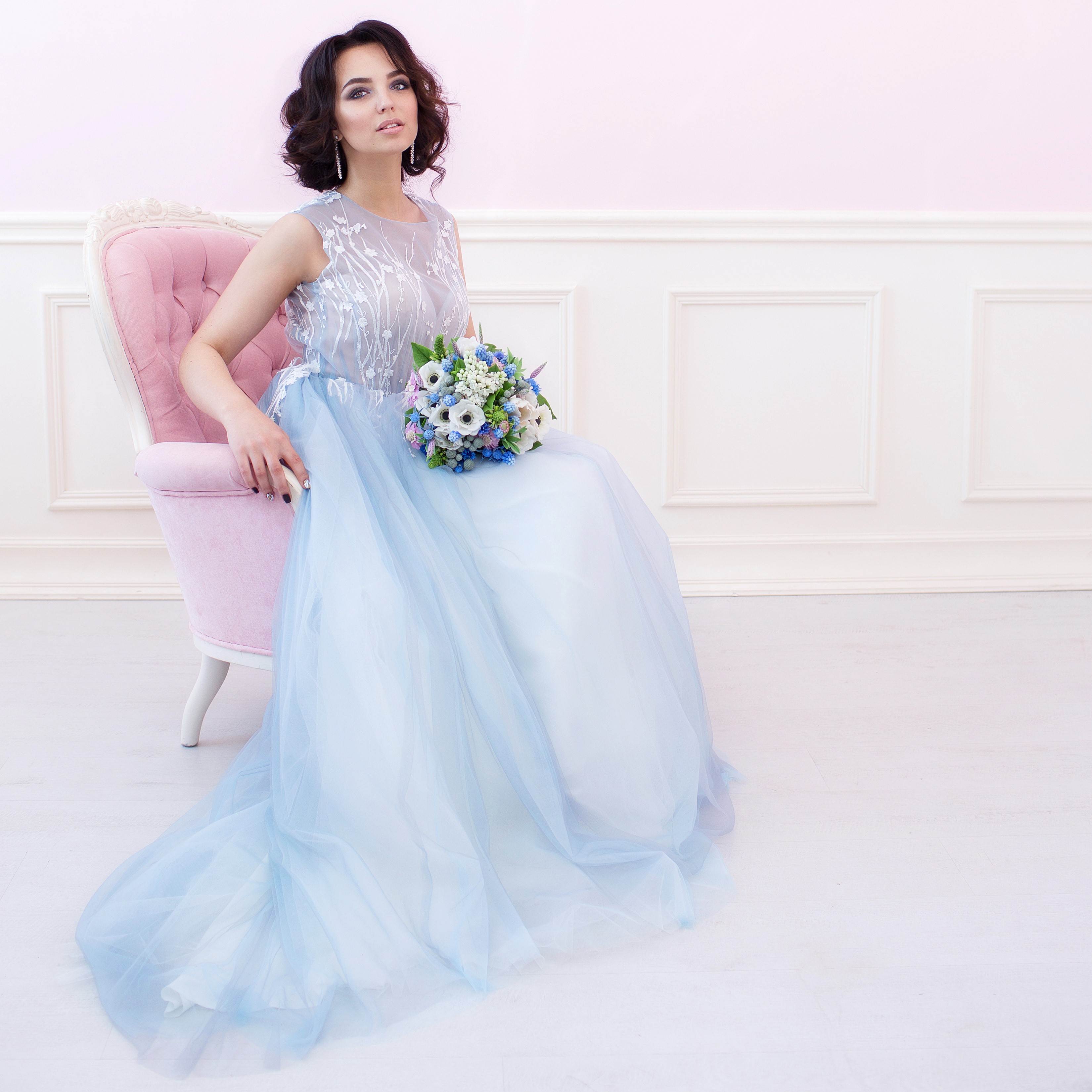 Woman in a blue dress holding a bouquet sitting in a pink armchair HD Wallpaper