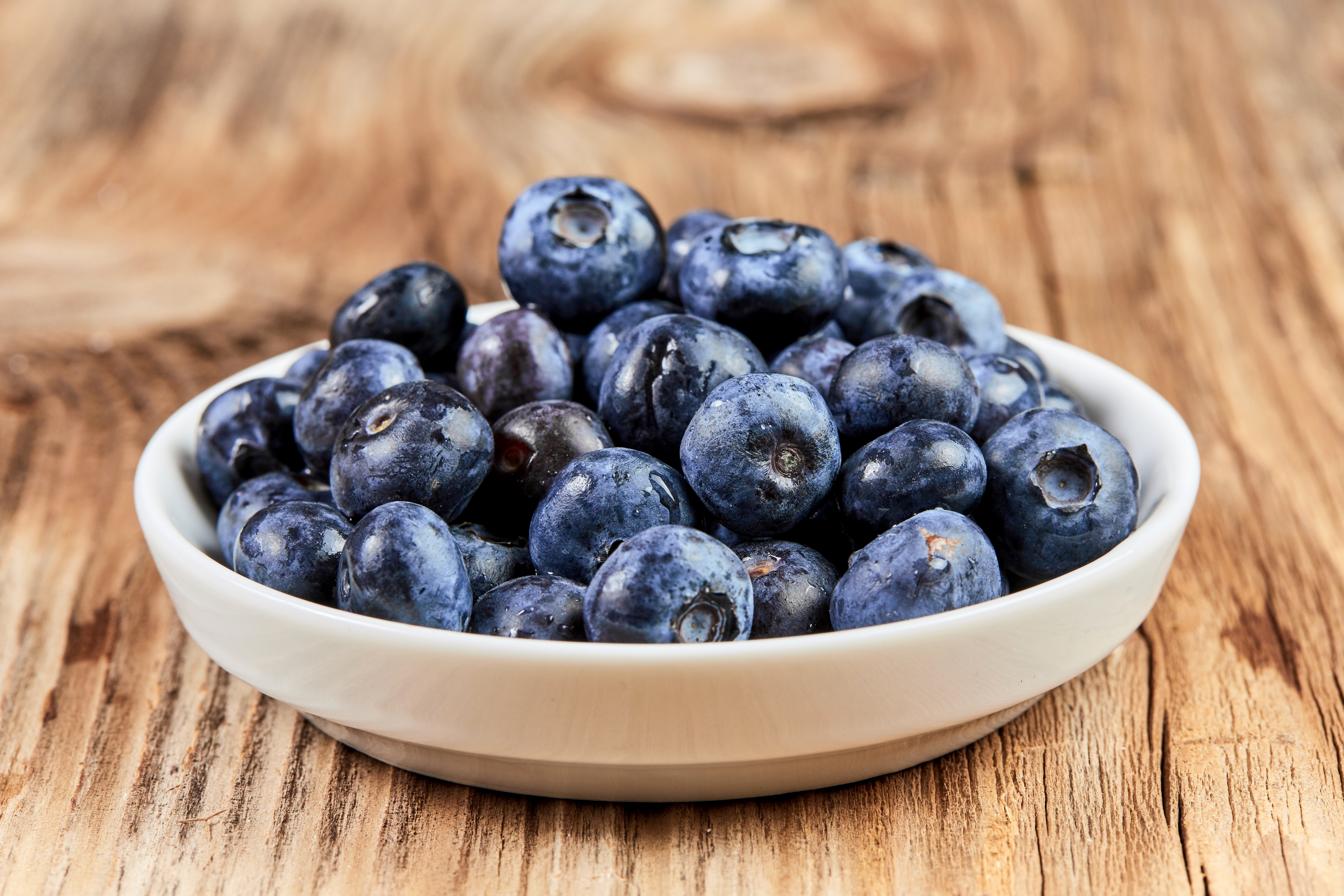 Blueberries in a white bowl on a wooden table HD Wallpaper