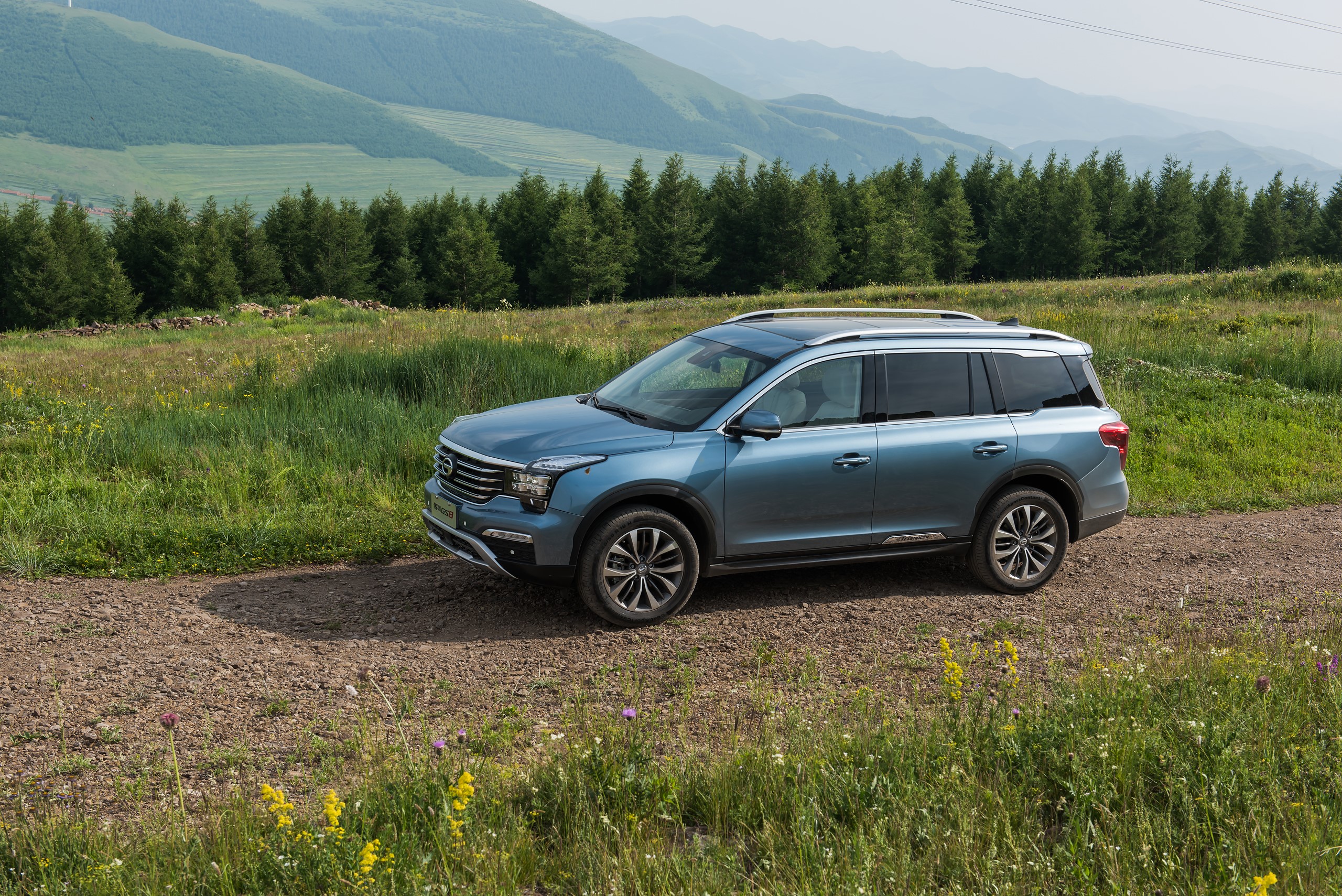 Light Blue 2016 Trumpchi GS8 SUV on a dirt road HD Wallpaper