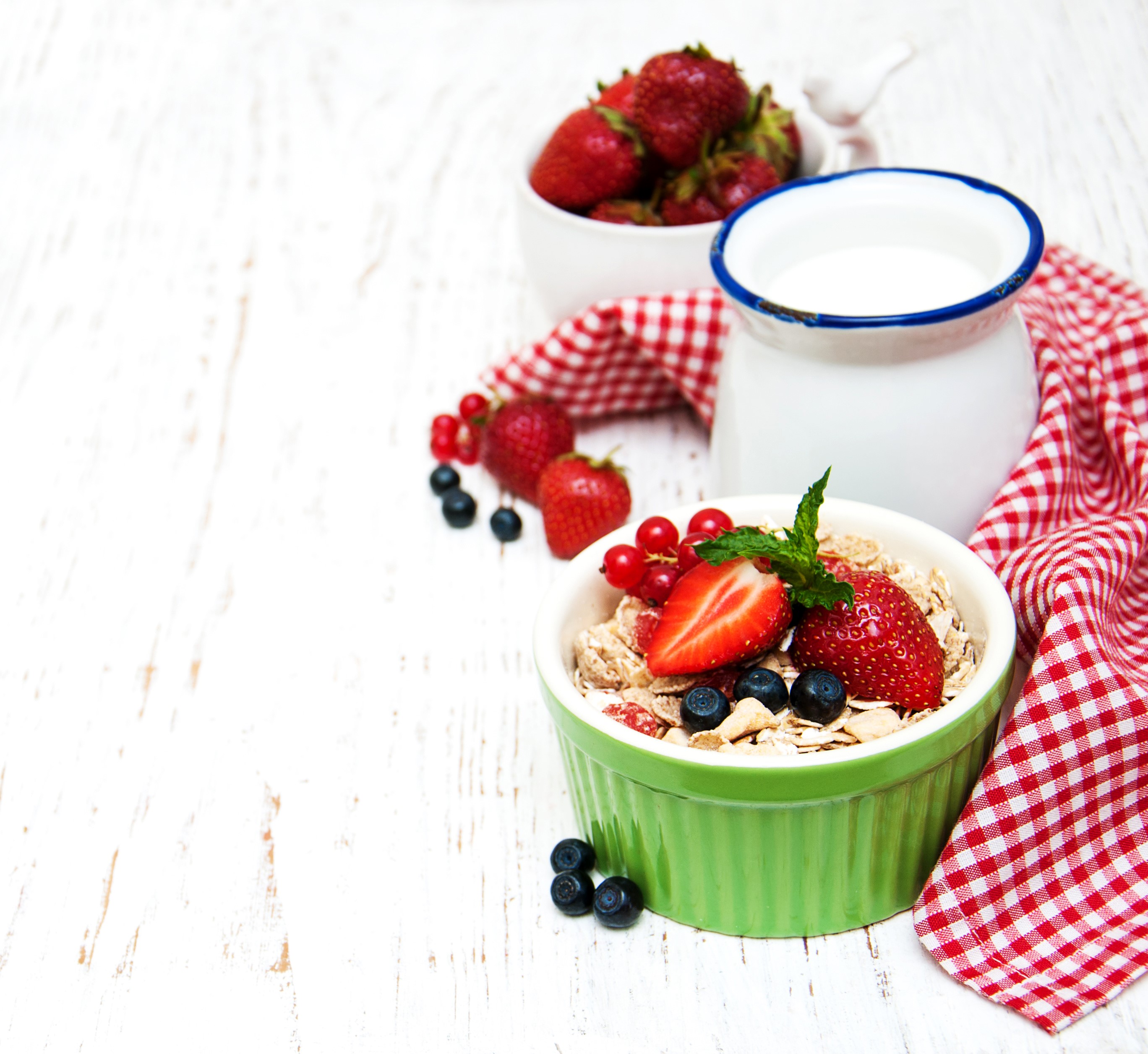 Muesli with strawberries, blueberries, and red currants in a bowl with a jug of milk HD Wallpaper