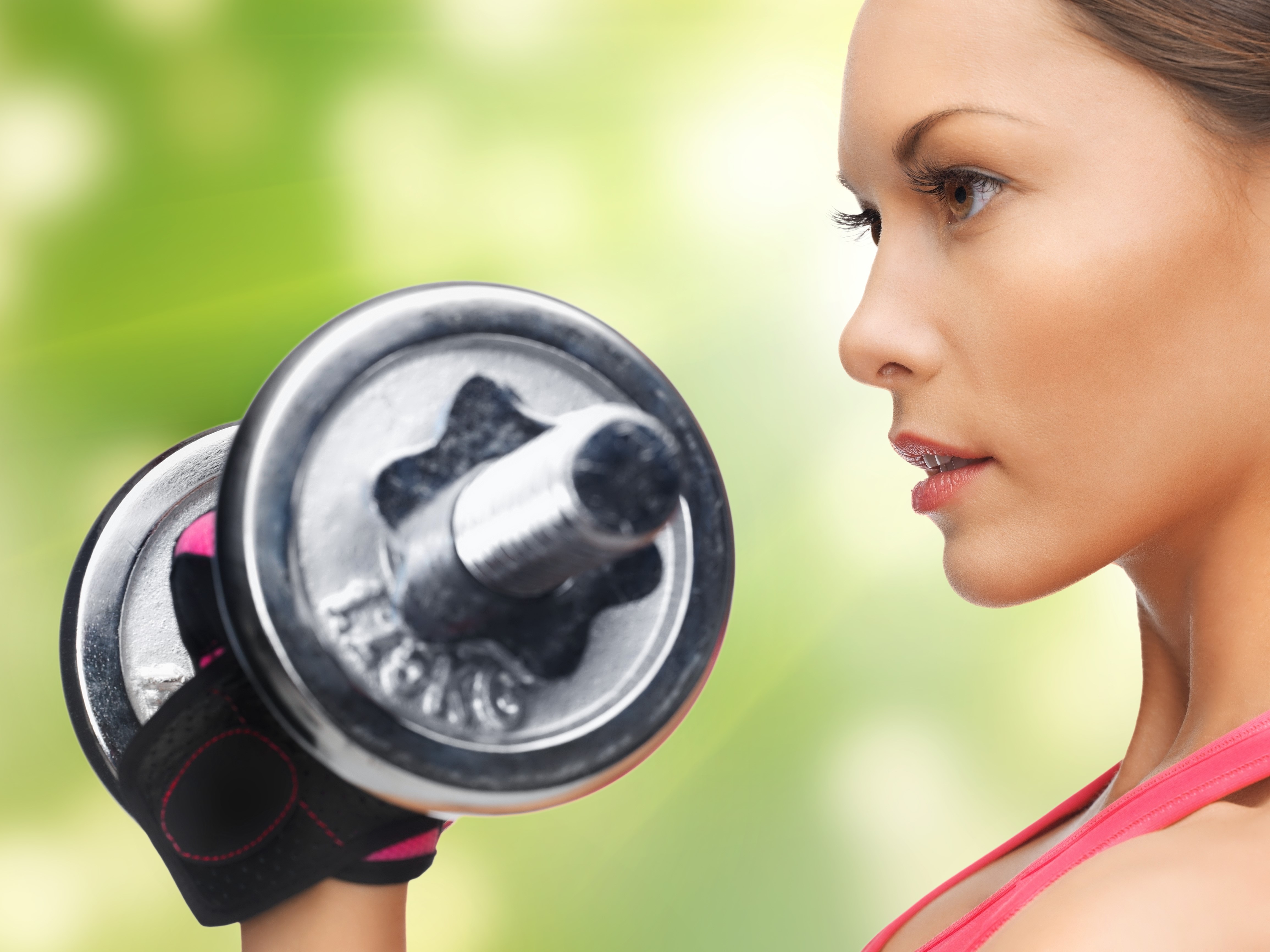Woman lifting dumbbell with green background HD Wallpaper