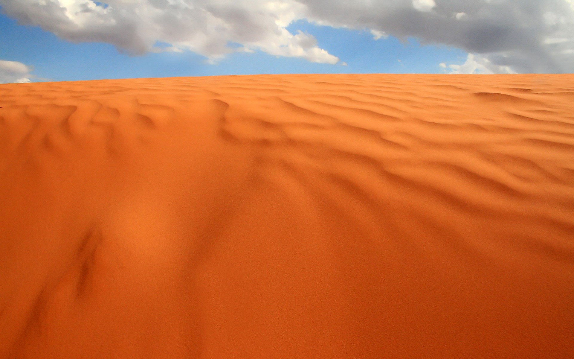 Desert sand dunes under a cloudy sky HD Wallpaper
