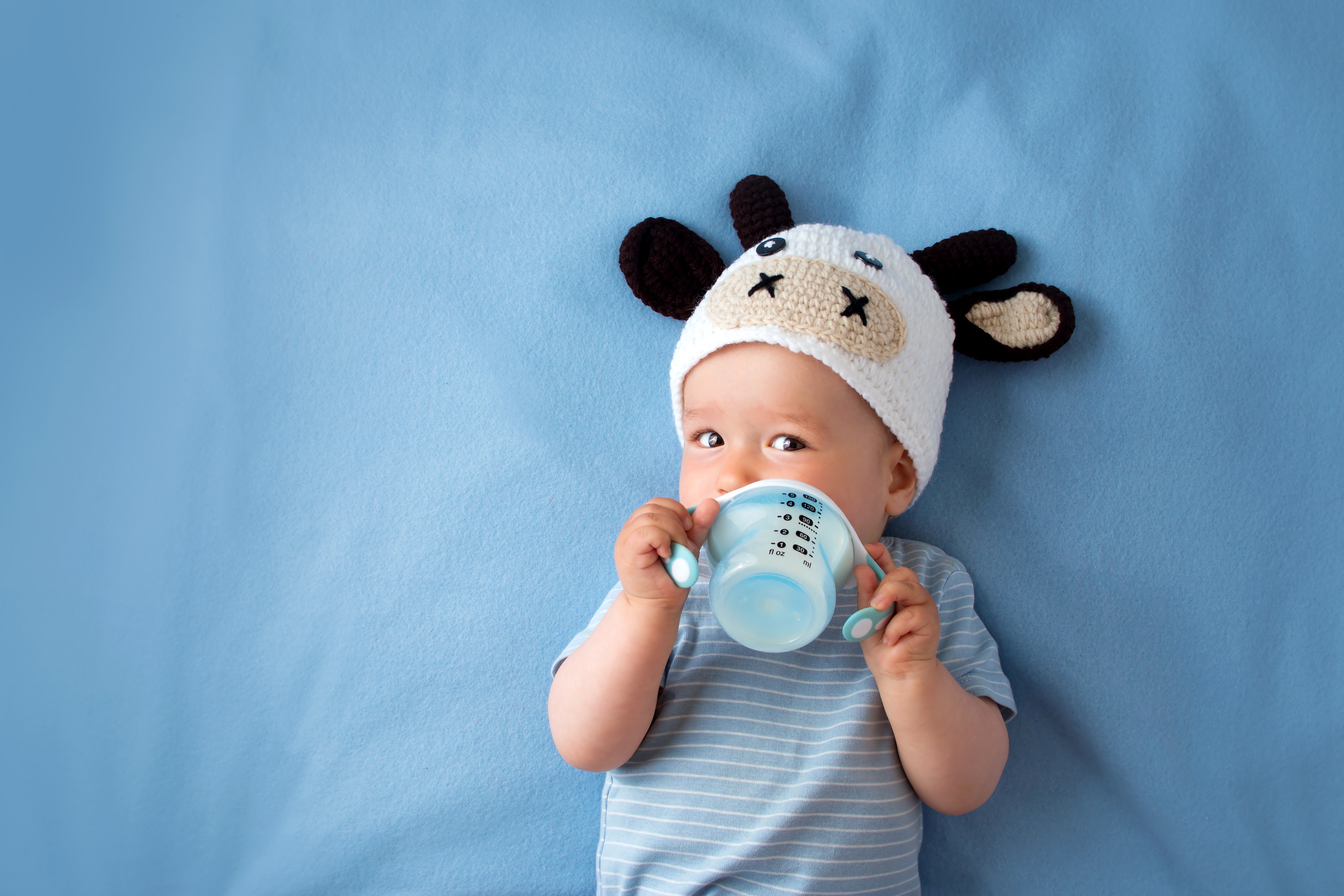 Baby wearing a cow hat drinking from a bottle HD Wallpaper